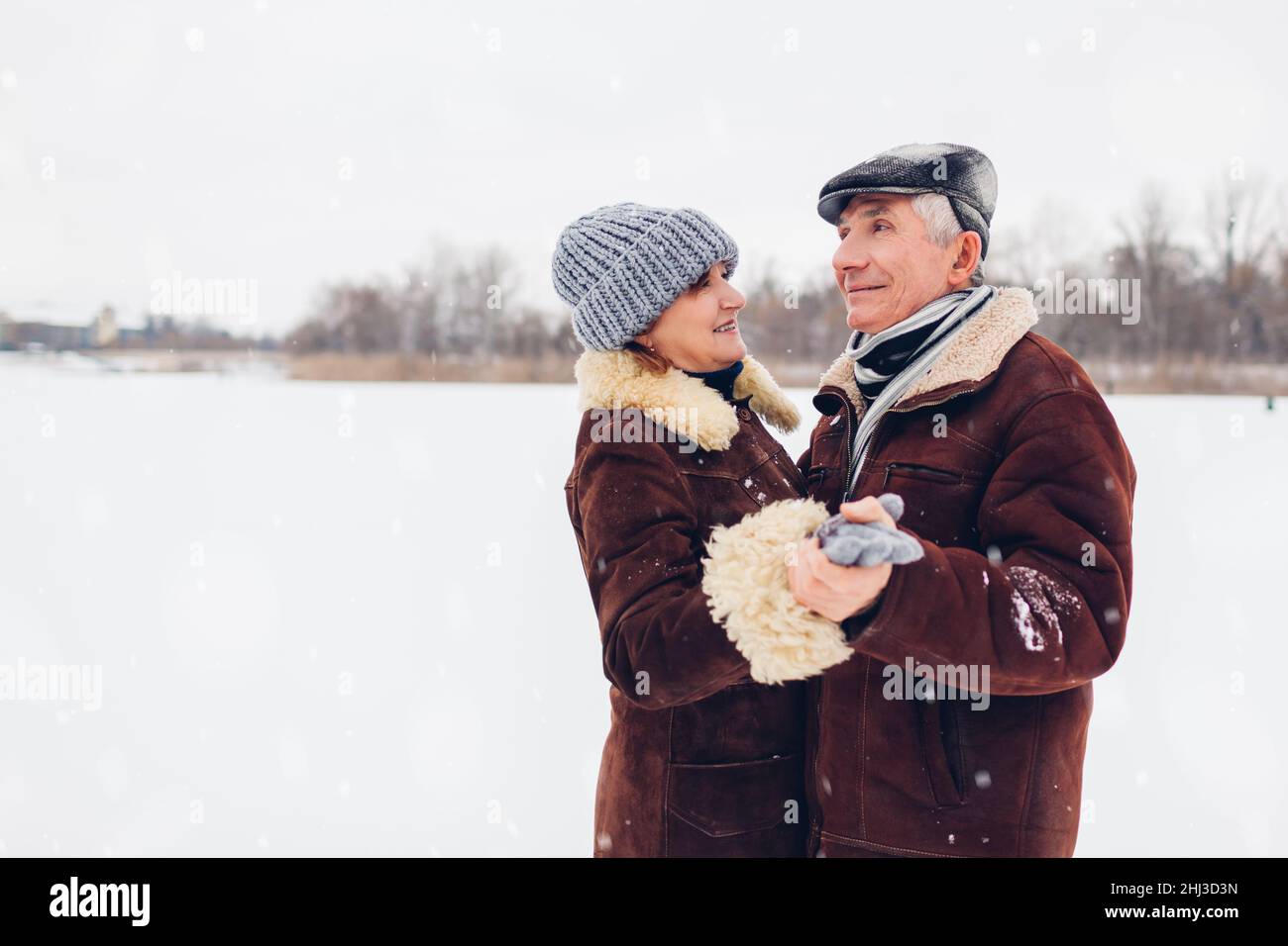 Ältere Familienpaare tanzen bei schneebedecktem Winterwetter im Freien. Ältere Menschen haben Spaß beim Gehen. Valentinstag Stockfoto