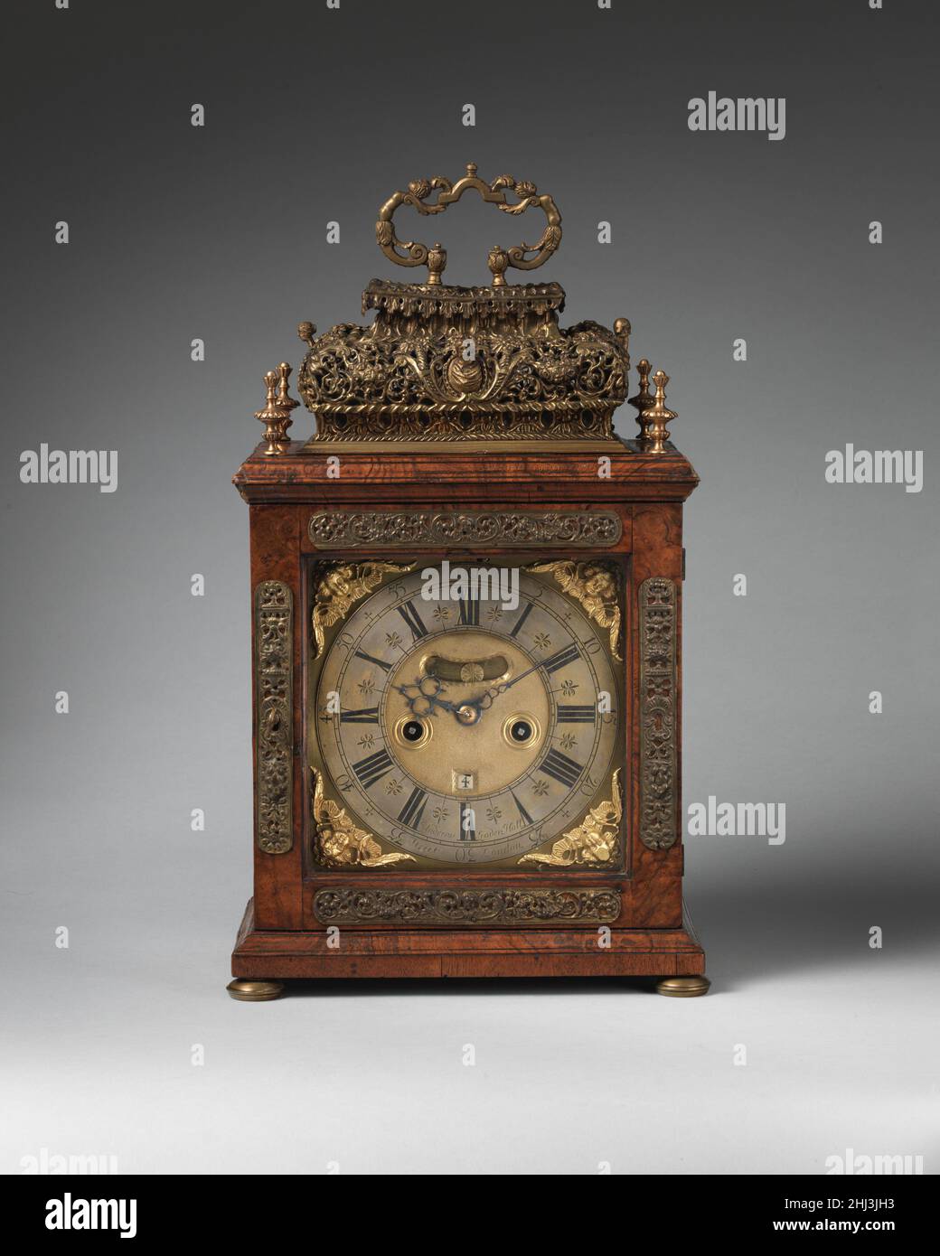 Tisch- oder Halteruhr 1690 Uhrmacher: John Andrews Diese Art von Uhrwerk hat ein kurzes Pendel, wodurch die Uhr klein genug ist, um auf einem Regal oder einer Halterung zu sitzen. Die Uhr hat eine gravierte Rückplatte, die im späten siebzehnten Jahrhundert in London modisch war. Die Gravur wurde von einer relativ kleinen Gruppe von Spezialisten durchgeführt, die unterschiedliche Fähigkeiten hatten. Ihre Arbeit ist unsigniert und bleibt zum größten Teil anonym. Die Unterschrift ist hier die des Uhrmachers, des Uhrmachers John Andrews. Tischuhr oder Halteruhr. Großbritannien, London. 1690. Vergoldetes Messing und Stahl; Gehäuse: Walnu Stockfoto