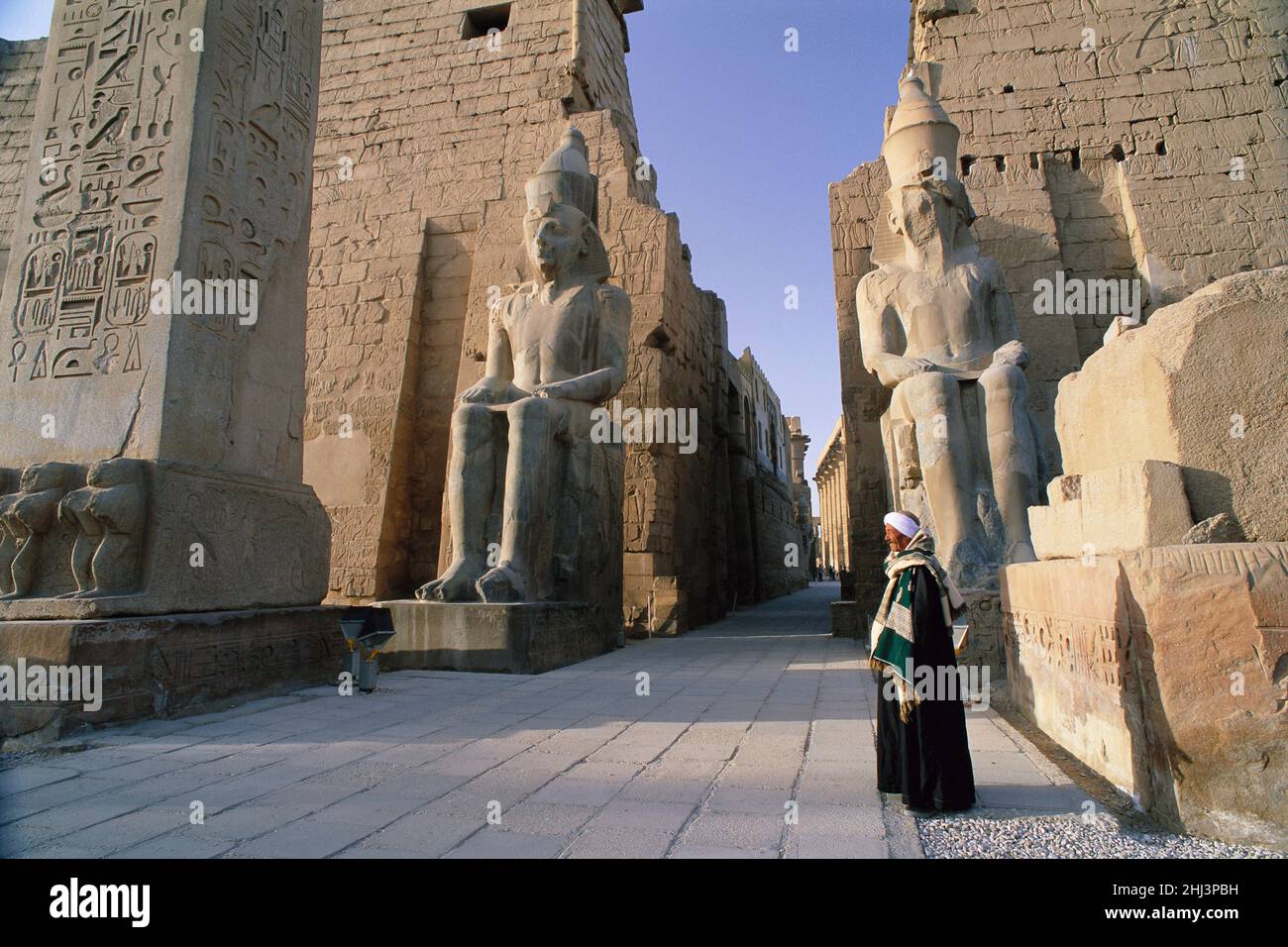Ägyptischer Mann, der am Eingang zum Luxor-Tempel, Luxor, Ägypten, steht Stockfoto