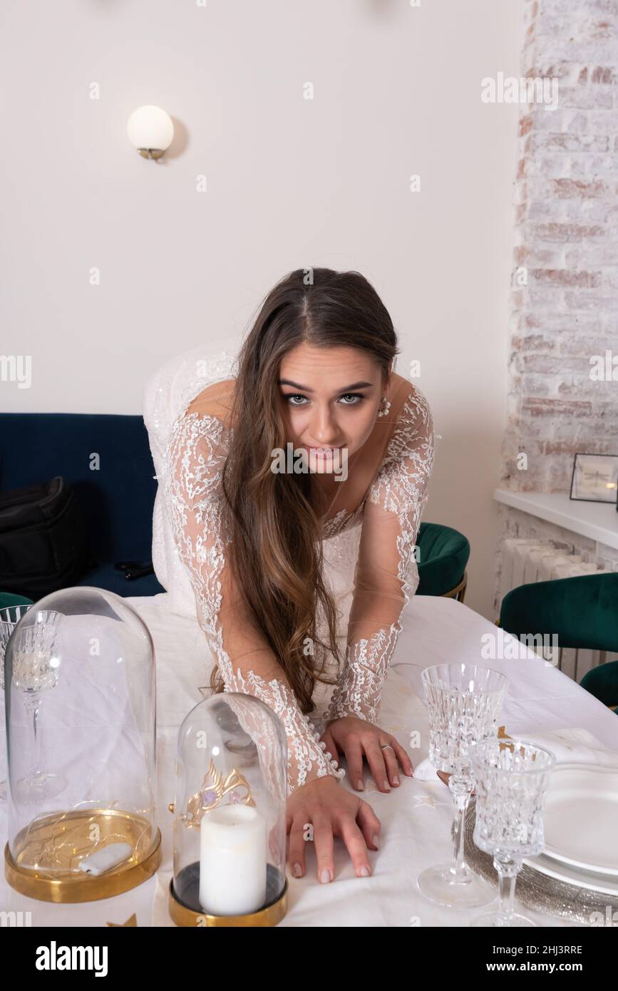 Die Braut kriecht wie eine Katze auf den Tisch. Hochwertige Fotos Stockfoto