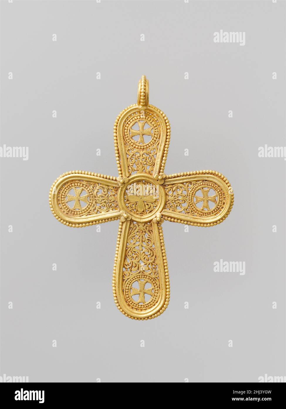 Anhänger des goldenen Kreuzes 500–700 Byzantine Ein wohlhabender Mensch oder ein Mitglied des Klerus mag dieses elegante Kreuz getragen haben, das größte, das bekanntermaßen in opus interrasile gearbeitet wurde. Als das Christentum die dominierende Religion in der byzantinischen Gesellschaft wurde, wurde christliche Bildsprache zunehmend auf Schmuck gefunden. Kreuze erscheinen im fünften Jahrhundert; die Jungfrau Maria, Heilige, Engel und andere heilige Figuren wurden im sechsten Jahrhundert populär. Die Bilder wurden gedacht, um den Träger zu schützen, Hilfe in Gebeten, und sogar Wunder zu tun.. Anhänger Mit Goldenem Kreuz. Byzantinisch. 500–700. Gold. Metallarbeiten-Gold Stockfoto