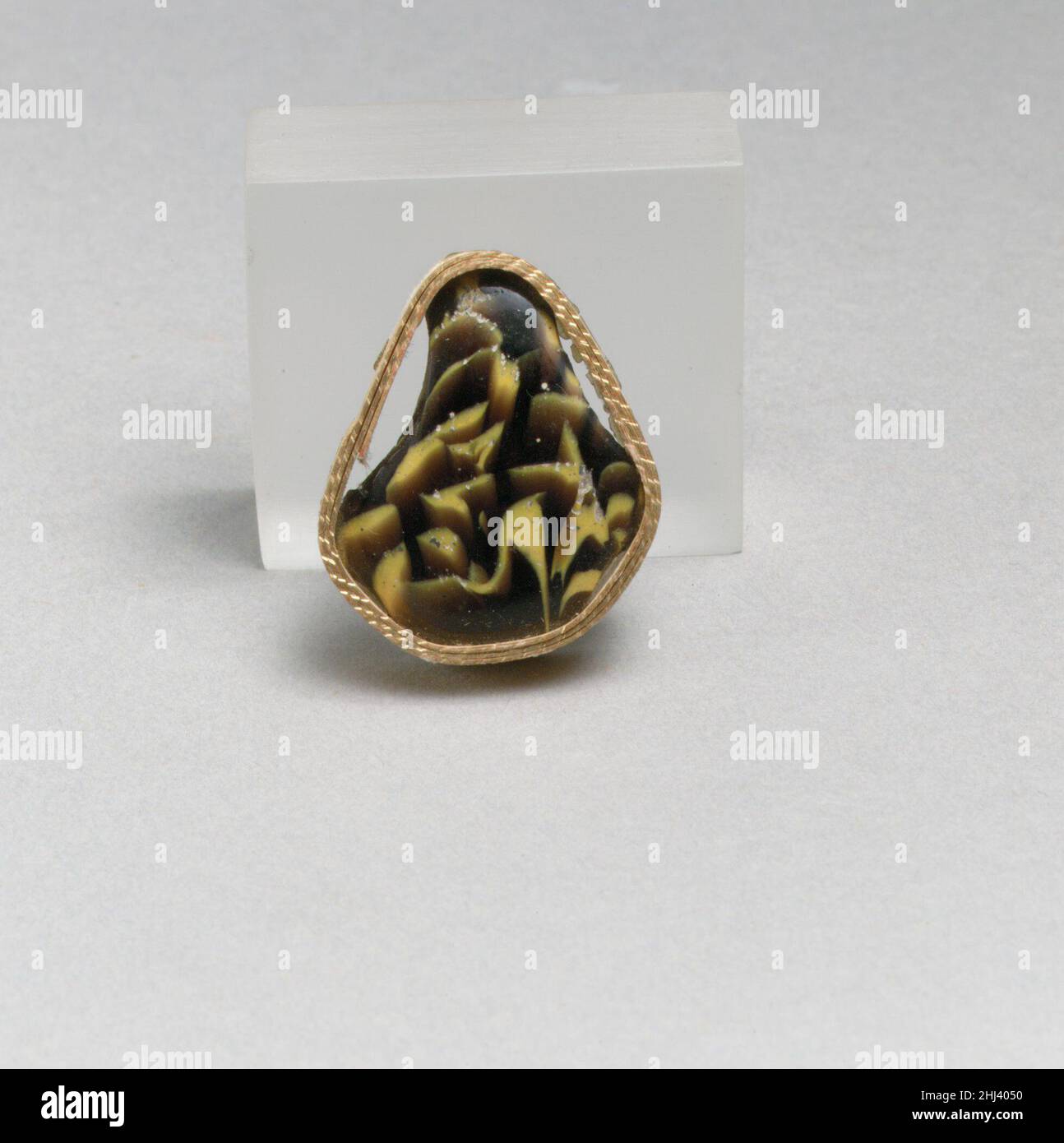 Glasmosaikfragment Ende des 1st. Jahrhunderts v. Chr.–Anfang des 1st. Jahrhunderts n. Chr. römisches Körperfragment.Durchscheinendes tiefviolettes, schokoladenbraunes und opakes Gelb.konvex geschwungene Seite.Mosaikmuster, das aus Abschnitten eines einzelnen Rohres in purpurem Boden mit großen unregelmäßigen gelben Streifen und Wirbeln gebildet wurde.Polierte Außenseite und Kanten; Lochfraß von Oberflächenblasen an der Außenseite; Stumpfen und Lochfraß im Innenraum. In eine tropfenförmige Form geschnitten, vielleicht in der Antike. Glasmosaikfragment 257277 Stockfoto