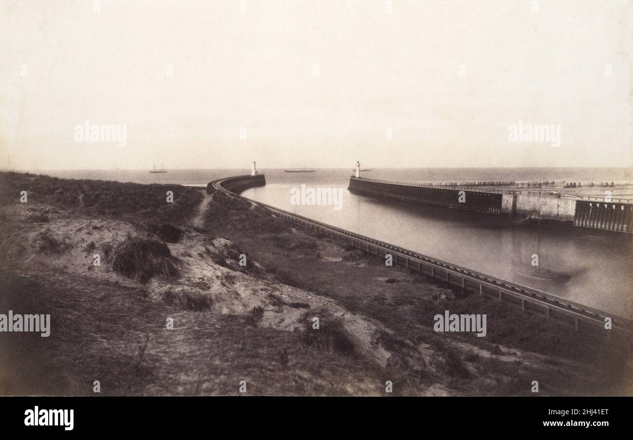 [Eingang zum Hafen von Boulogne] 1855 Edouard Baldus Französisch, geborenes Preußen Boulogne-sur-Mer, die Endstation der Eisenbahnlinie von Paris, war das Tor für Handel und Reisen zwischen dem viktorianischen England und dem Frankreich des Zweiten Kaiserreichs. Es war auch der Ankunftsort für den Staatsbesuch von Königin Victoria im Jahr 1855, und dieser außergewöhnlich reiche, subtile Druck stammt aus einem Album, das von Baron James de Rothschild, dem Besitzer der Linie, für die Präsentation vor dem kaiserlichen Hof bei dieser Gelegenheit in Auftrag gegeben wurde. Baldus's Foto, das die elegant konstruierten Anlegestellen zeigt, die Schiffe vom Ärmelkanal am sc vorbeiführten Stockfoto