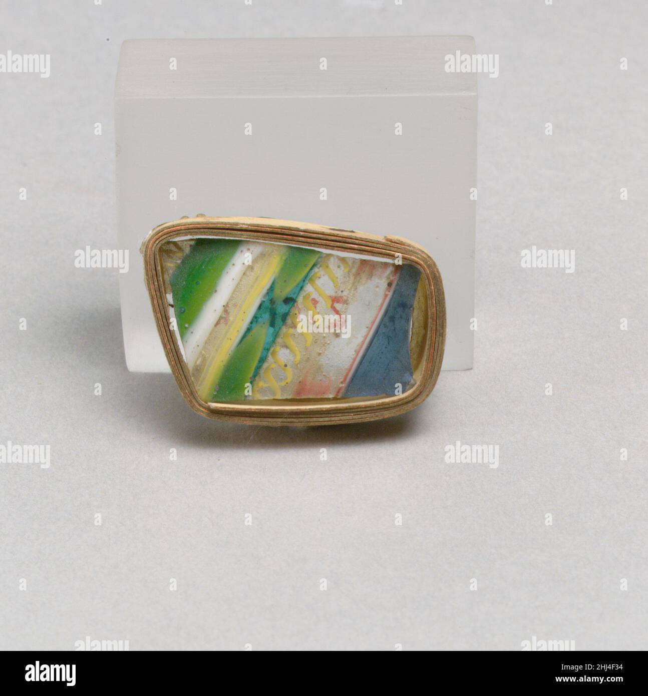 Glasstreifenmosaikfragment Ende des 1st. Jahrhunderts v. Chr.–Anfang des 1st. Jahrhunderts n. Chr. römisches Körperfragment.Durchscheinendes Blau, Türkisblau und undurchsichtiges Gelb, grün, violett, undurchsichtig, Ziegelrot, weiß, gelb und farblos.konvex geschwungene Seite, an einer Ecke gedreht (unten?).mit Parallel (horizontal?) verziert Blaue Bänder mit dünnen weißen und roten Linien unten, farbloses Glas mit roten Streifen, farbloses Glas mit doppelten gelben Spiralfäden, streifengrün, gelb, weiß, grün, Und farbloses Glas mit doppelten gelben Spiralfäden.Pinprick Blasen; außen poliert, mit Lochfraß Stockfoto