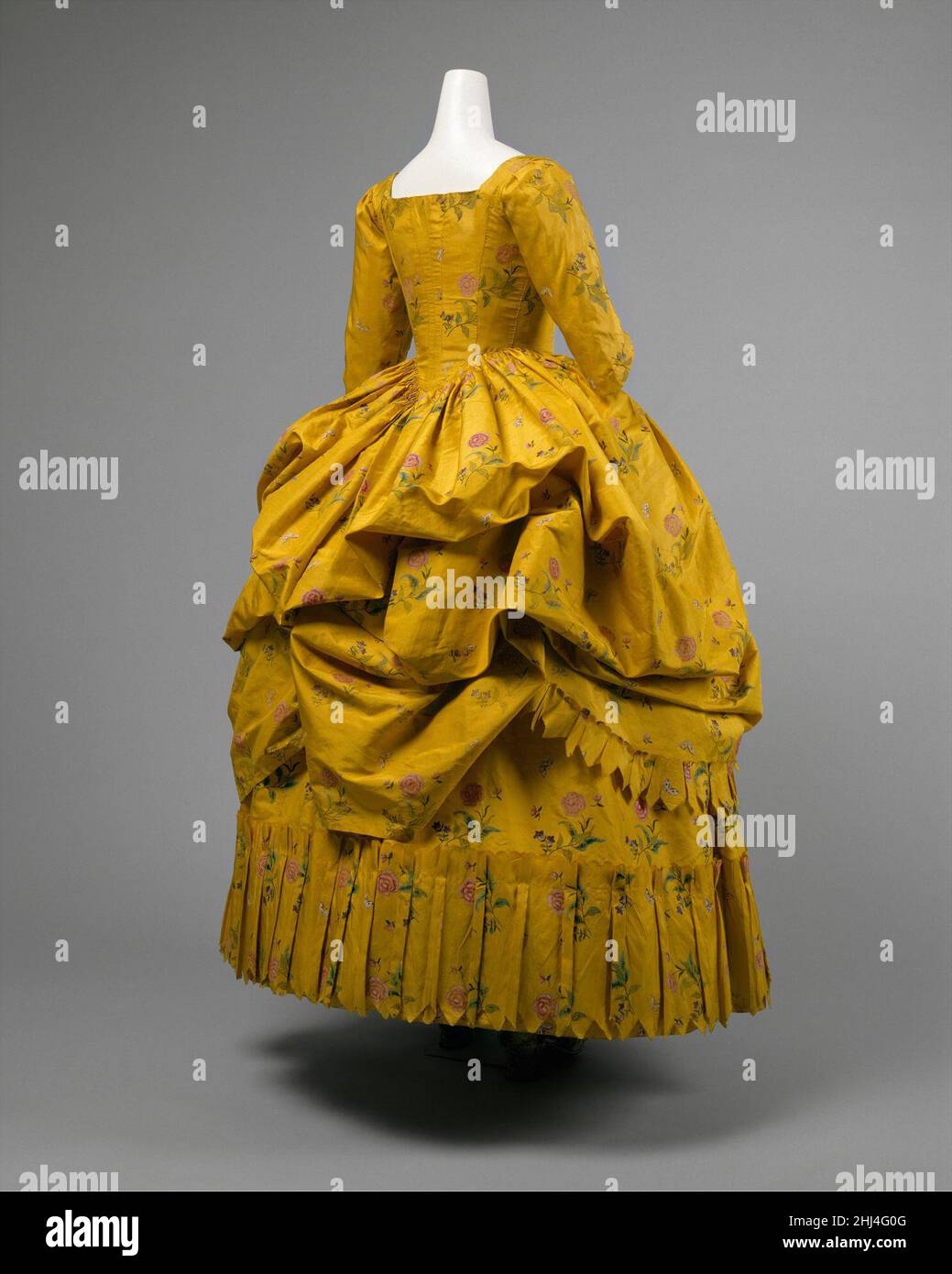 Robe à la Polonaise 1780–85 Amerikaner das Polonaise-Kleid kam 1770s erstmals in Mode. Es war ein Stil von Kleid mit einem eng anliegenden Mieder und die Rückseite des Rockes in drei separaten gepufften Abschnitten gesammelt, um den Petticoat unten zu offenbaren. Die Methode des Aufhängeens des Gewebes variierte. Am häufigsten hatte das Kleid Reihen von kleinen Ringen im Rock genäht, durch die eine Schnur vom Saum bis zur Taille verlief. Alternativ würden Bandbinder verwendet werden, wobei die Bänder dekorative Schleifen bilden. In einigen Fällen wurde der Rock jedoch durch einfache Kordeln an der Innenseite der Taille des Kleides und an Ort und Stelle gehalten Stockfoto