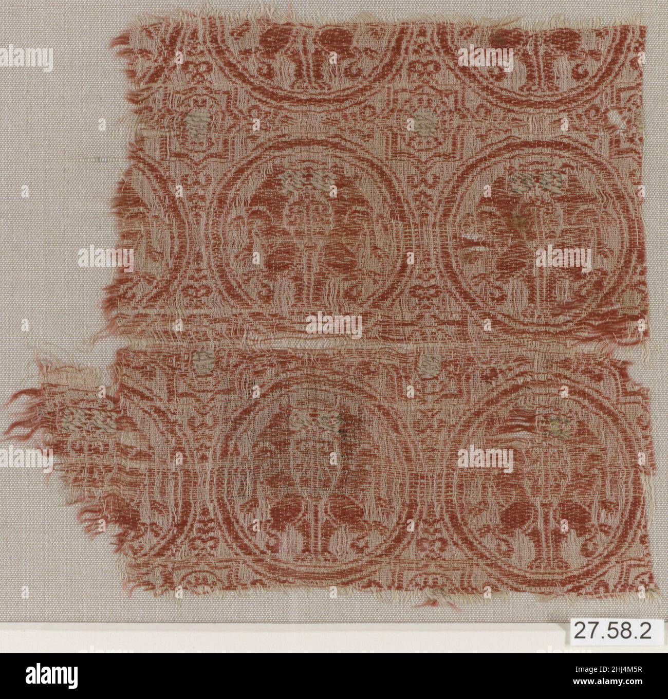 Textile Fragment Ende des 12th.–Anfang des 13th. Jahrhunderts die Dekoration auf diesem Textilfragment besteht aus kreisförmigen Medaillons mit Bildern von zugeschürften Vierbeiner, die auf ihren Hinterbeinen stehen. Die Leere zwischen den Körpern der Tiere enthält eine pflanzenähnliche Form, die auf den Baum des Lebens hindeutet. Abwechselnd mit den Medaillons wird eine Reihe von achtspitzigen Starts dargestellt - ein traditionelles spanisches Motiv. Darstellungen von Tierformen innerhalb von Rahmungseinrichtungen waren auch gängige dekorative Motive in Objekten, die im Mittelalter rund um das Mittelmeer entstanden sind, und finden sich in Ornamenten aus Holz, Textilien, Elfenbein, Metallarbeiten und Stockfoto