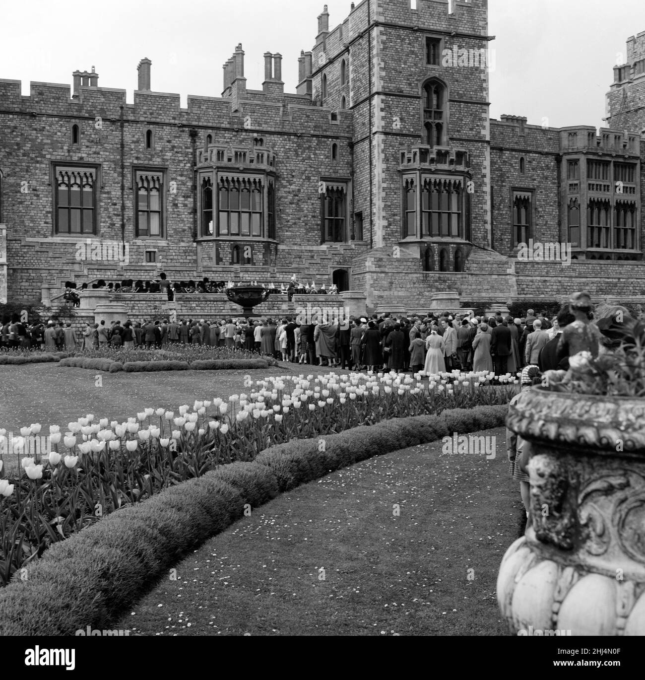 Mehrere hundert Menschen gingen heute zum Schloss Windsor, um den Bands zuzuhören, die auf der Terrasse der Royal Apartments spielten. Die königliche Familie konnte durch die Fenster gesehen werden, auch sitzen und der Musik lauschen. Sie spielten zunächst „Happy Birthday“, um den Geburtstag der Königin zu feiern. 21st. April 1957. Stockfoto