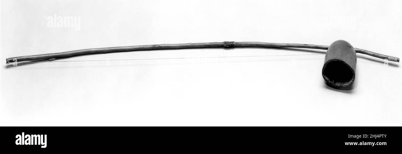 Musikalischer Bogen Westafrikanisches Ende des 19th. Jahrhunderts der musikalische Bogen, ein Holzstab, der mit einer Saite versehen und mit einem Stock angezapft ist, ist einer der ältesten Instrumentenarten. Die Klänge der vegetalen, metallischen oder Kordelstring können durch einen Kürbis-Resonator gegen die Brust gehalten oder im Mund resoniert werden. Es ist weit verbreitet und afrikanische Versionen wurden von versklavten Völkern nach Amerika gebracht, die es in Brasilien verwendeten (berimbau), um Capoeira, einen Kampfkunsttanz, aufzuführen. Musical Bow 501113 Stockfoto