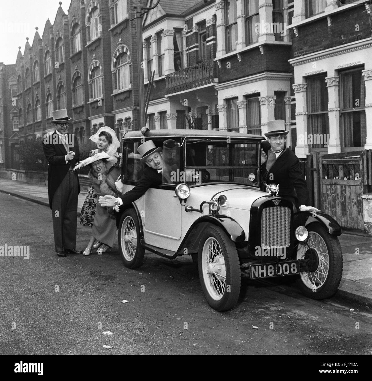 In der Stanlake Road hatte Shepherd's Bush 'The Larkins' von ATV-Ruhm eine Drehsitzung für ihre nächste Folge, in der sie alle verkleidet sind, um in David Kossoff's Buttercup, einem sehr vorkriegsgekleideten Austin 7, in leuchtendem Gelb und Schwarz gemalt zu werden. Im Fahrersitz gibt David Kossopf optimistisch sein Signal, während Ronan O'Casey, Ruth Trouncer und Peggy Mount auf der linken Seite das Auto schieben. Shaun O'Riordan gibt rechts vom Bild eine Hand. 20th. Februar 1959. Stockfoto