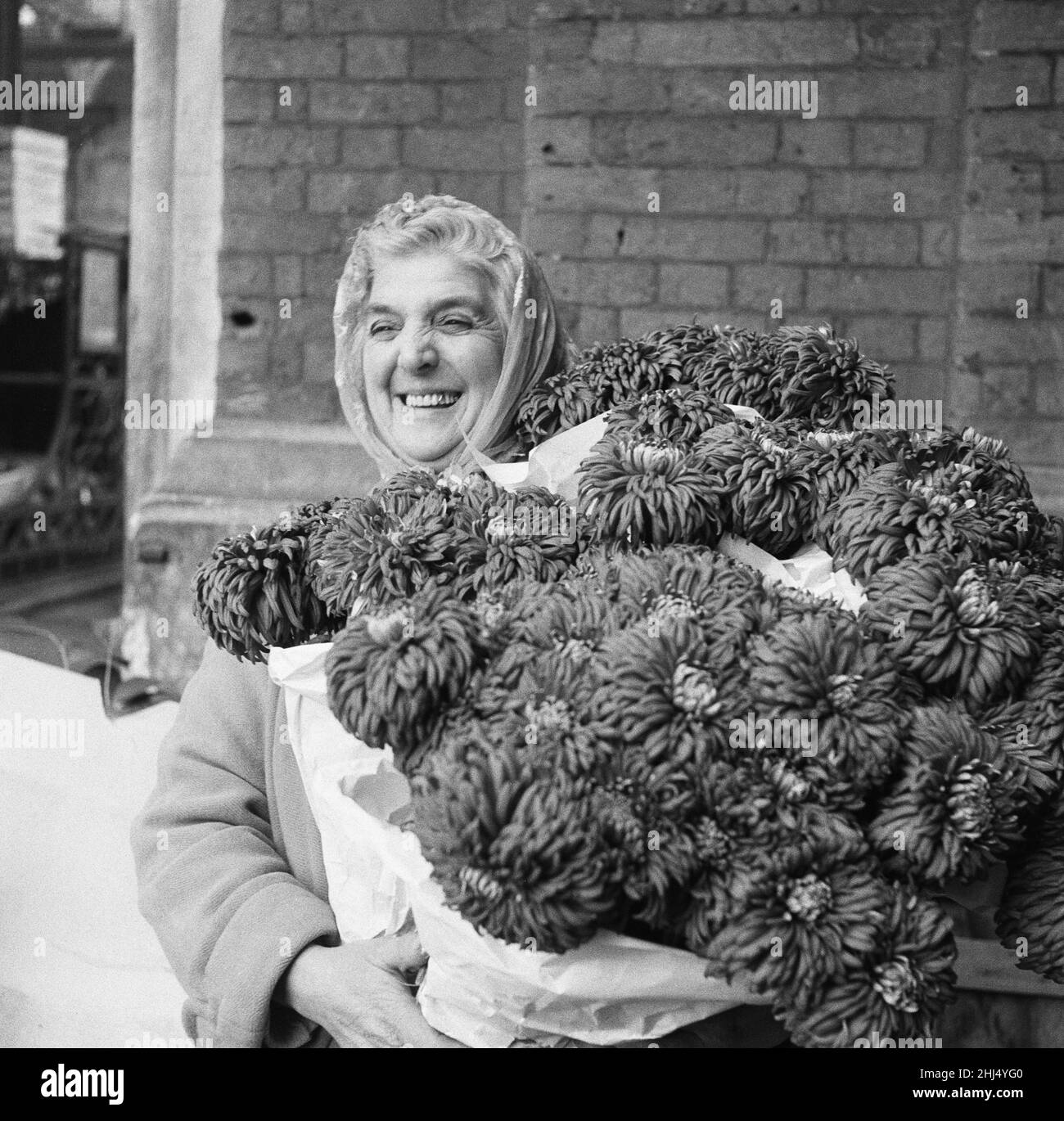 The Ladies of Covent Garden, Covent Garden Market, London. Eine Dame genießt es, ihre Blumen auf dem Covent Garden Market, London zu halten. Foto vom 9th. November 1960. Stockfoto