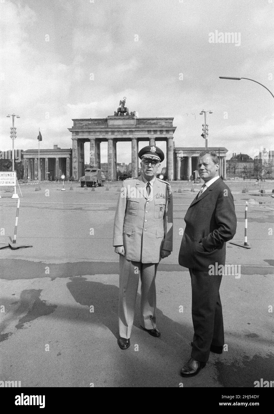 General Bruce C Clarke, Oberbefehlshaber der US-Armee in Europa am Brandenburger Tor mit dem West-Berliner Bürgermeister Willy Brandt, drei Tage nach Beginn des Baus der Berliner Mauer. Im Hintergrund ist eine schwergepanzerte Wasserstrahlwerfer aus Ostdeutschland mit einer auf die beiden Männer trainierten Strahldüse zu sehen. 16th. August 1961. Stockfoto