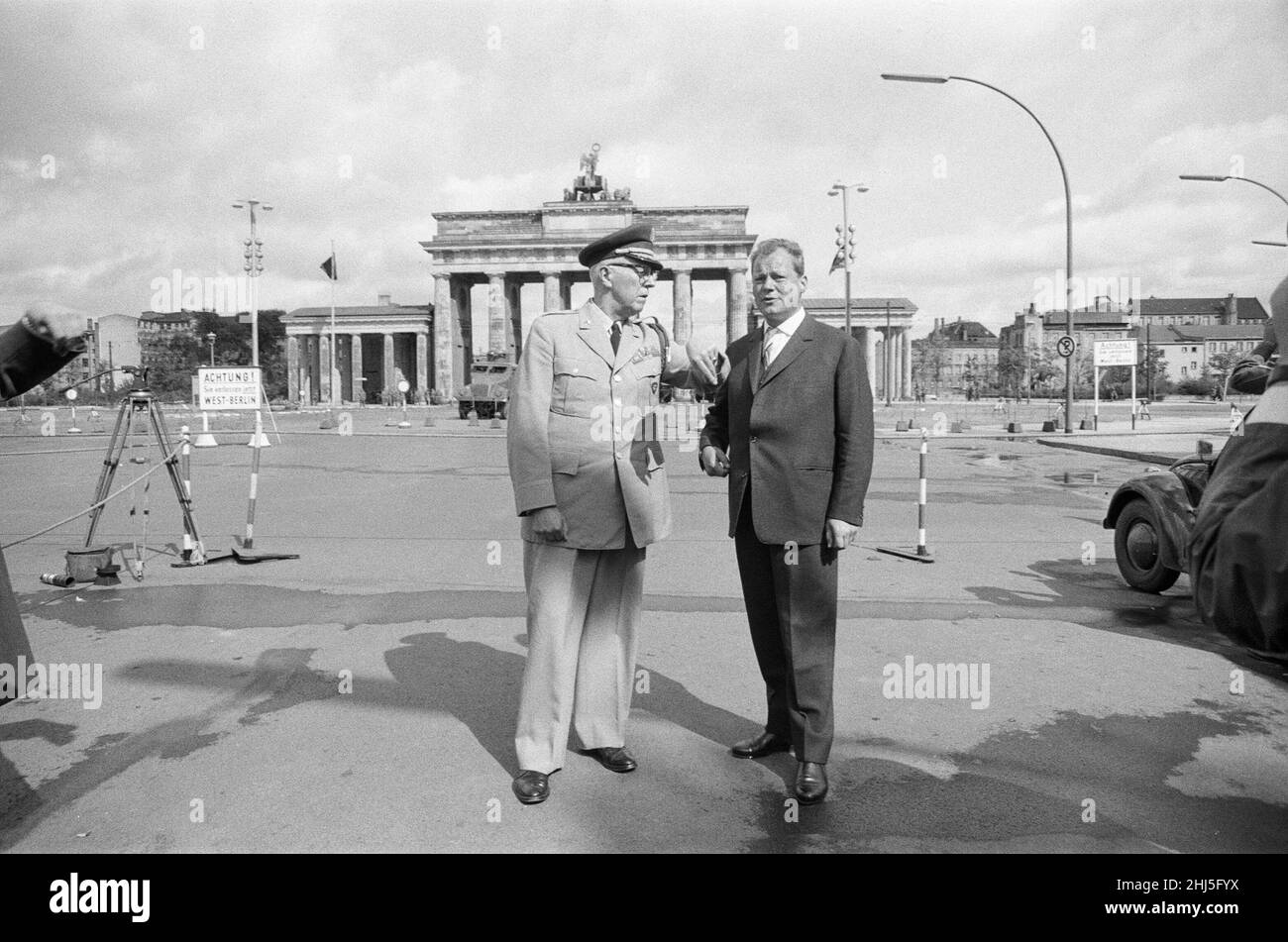 General Bruce C Clarke, Oberbefehlshaber der US-Armee in Europa am Brandenburger Tor mit dem West-Berliner Bürgermeister Willy Brandt, Drei Tage nach dem Bau der Berliner Mauer ist im Hintergrund eine schwergepanzerte Wasserstrahlwerfer aus der DDR mit einer auf die beiden Männer trainierten Strahldüse zu sehen. 16th. August 1961. Stockfoto