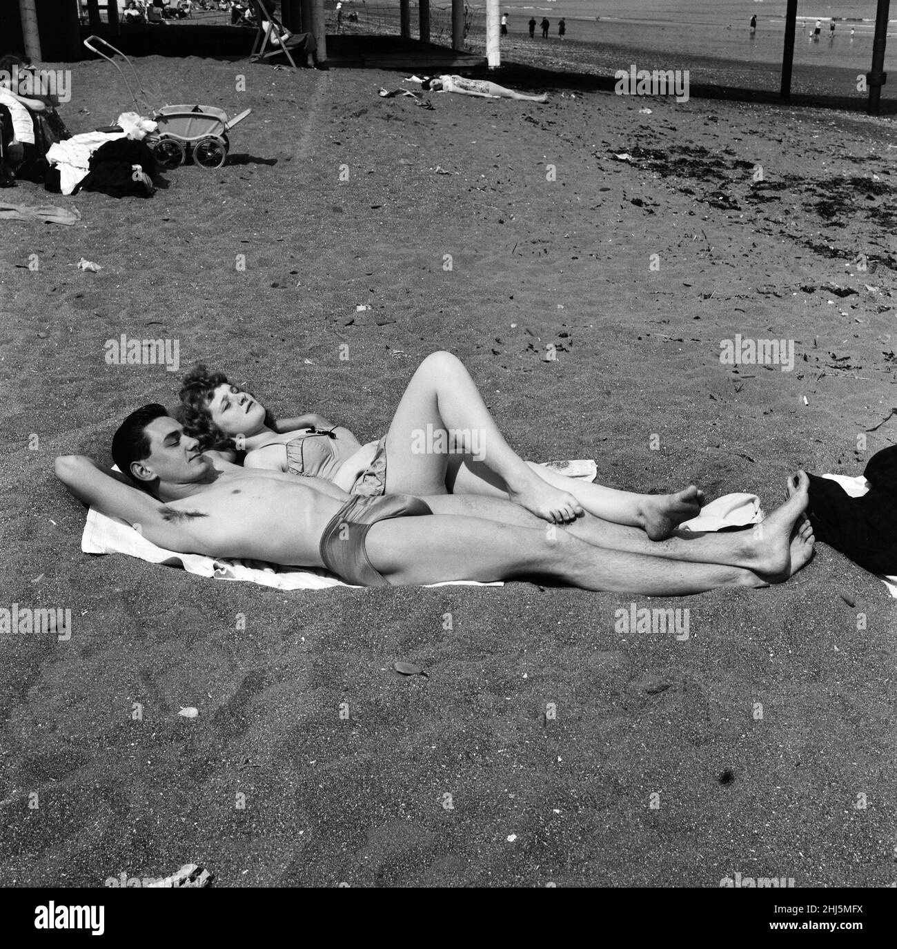 Die jungen Sonnenanbeter sind Mike Gardner, 19, ein Motormechaniker, der als Fußstütze von Valerie Vassallo, 17, der Schreibkraft von Plymouth, verwendet wird. Sie dösen in der Sonne auf Paignton, Devon. 18th Mai 1959. Stockfoto