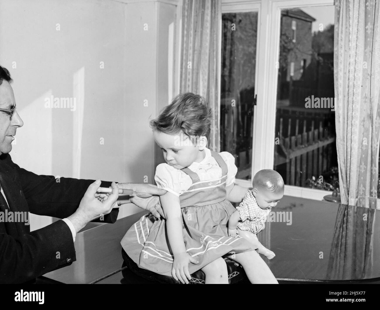 Eine junge Patientin schaut mit Beklemmung an, während sie ihre Polio-Impfung erhalten hat. Ca. April 1959 Stockfoto