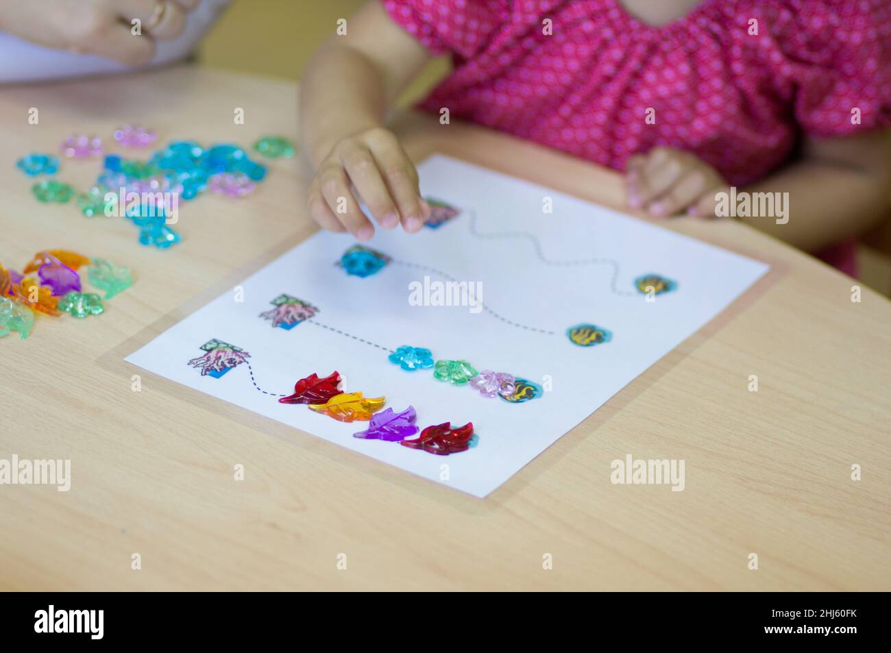Kinderhände spielen mit bunten Steinen, um feinmotorische Fähigkeiten zu entwickeln Stockfoto