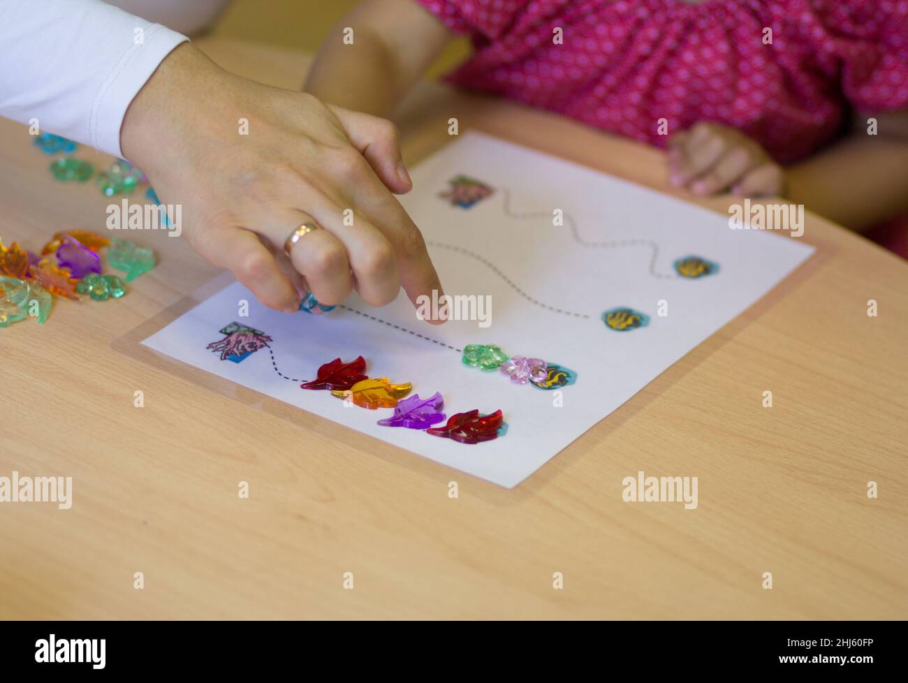 Kinderhände spielen mit bunten Steinen, um feinmotorische Fähigkeiten zu entwickeln Stockfoto