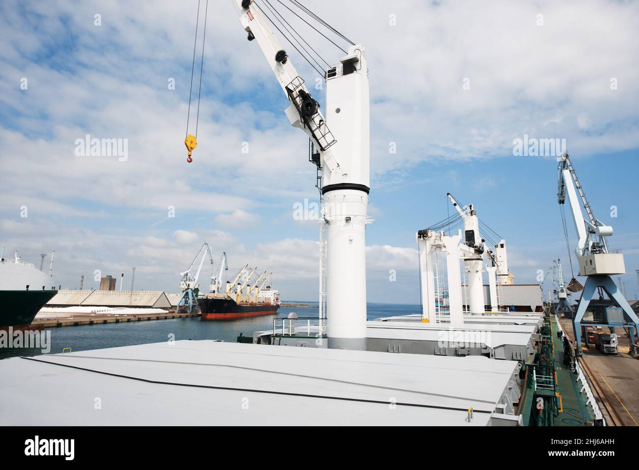 Die Werft schläft nie. Ein Foto von einem Hafen mit verankerten Schiffen mit Kranichen. Stockfoto