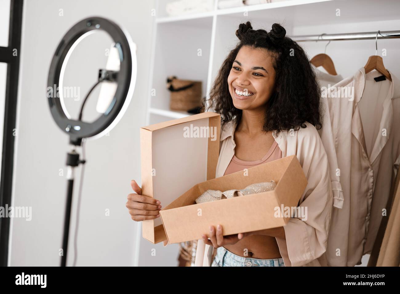 Glückliche junge afrikanische Frau Influencer Auspacken Paket mit Schuhen  stehen vor einer Kamera zu Hause Stockfotografie - Alamy