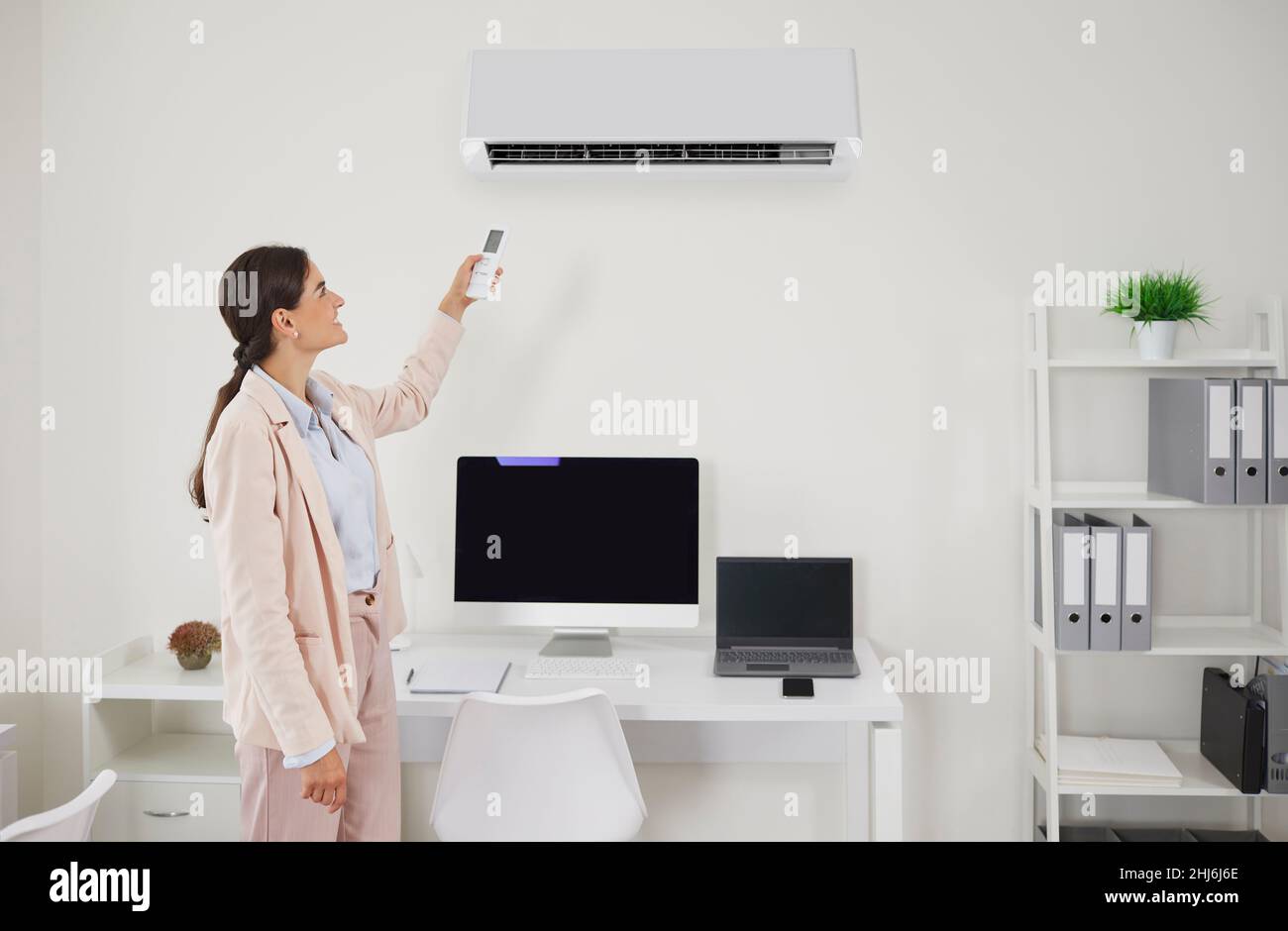 Glücklicher Büromitarbeiter schaltet die Klimaanlage um, um an heißen Sommertagen bei der Arbeit kühle Luft zu atmen Stockfoto