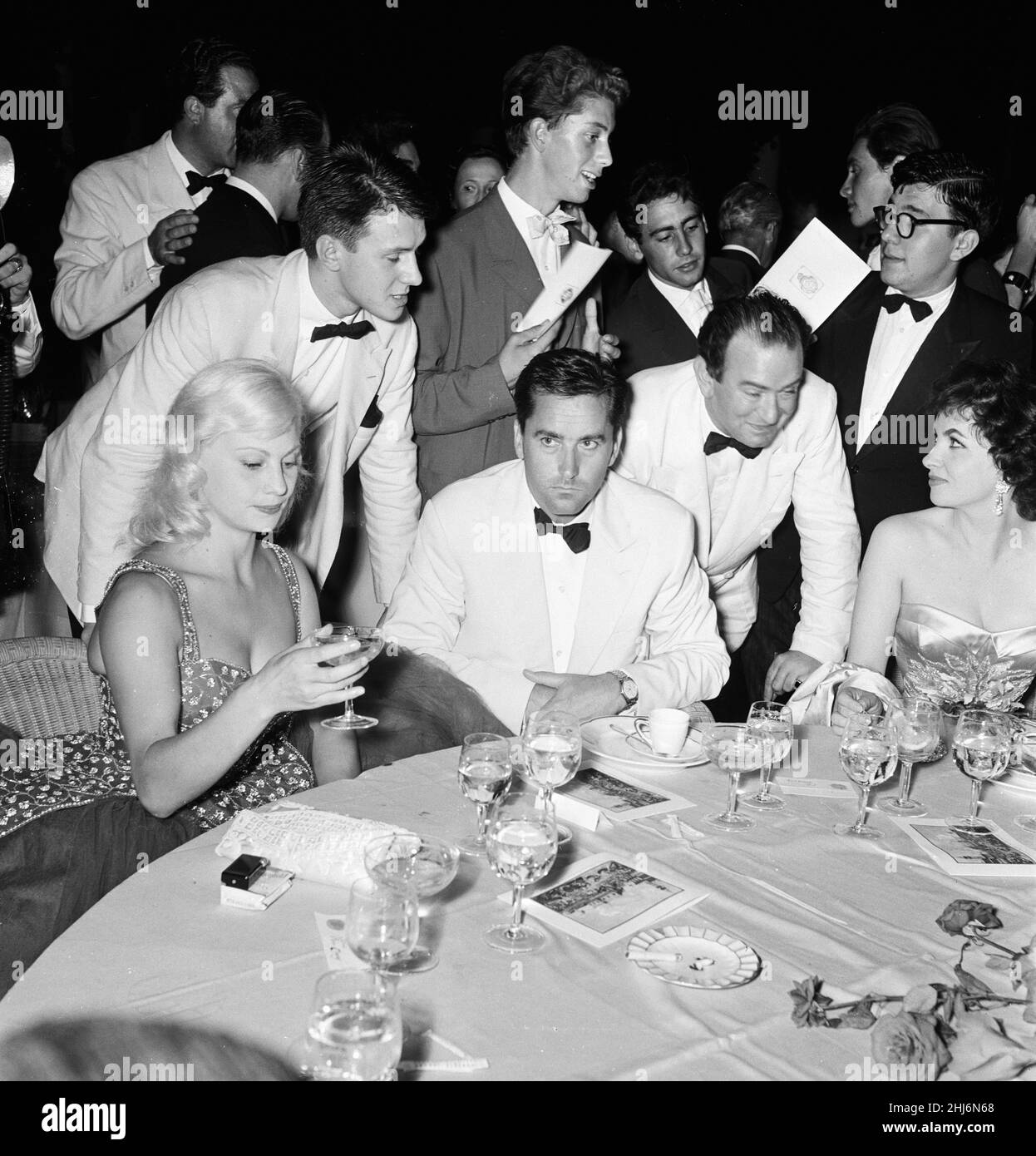1956 Venice Film Festival, Freitag, 31st. August 1956. Unser Bild Zeigt ... Die französische Schauspielerin Helene Remy (links) und die italienische Schauspielerin Gina Lollobrigida (rechts, ebenfalls Milko Skofic, Ehemann von Gina, und Bernard McElwaine, Bildjournalist am Sonntag (stehend, im Gespräch mit Gina). Stockfoto