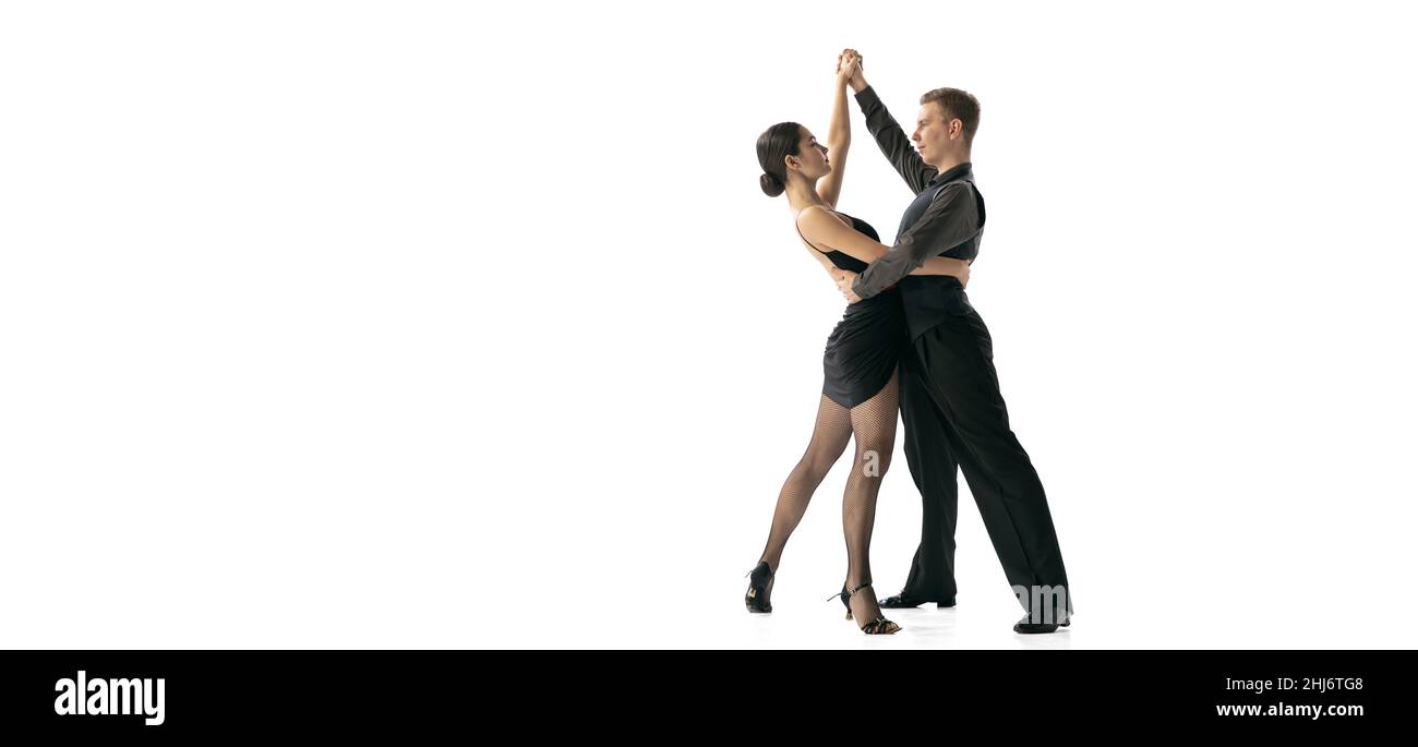 Flyer mit jungen Tänzerinnen, die argentinischen Tango tanzen, isoliert auf weißem Studiohintergrund. Künstler in schwarzen Bühnenkostümen Stockfoto