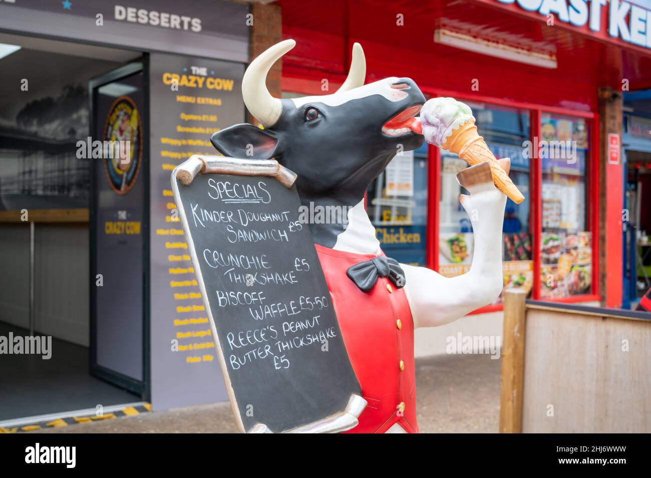 Eine Modellkuhwerbung mit einer speziellen Menütafel vor dem Crazy Cow Restaurant in der Küstenstadt Cromer UK Stockfoto