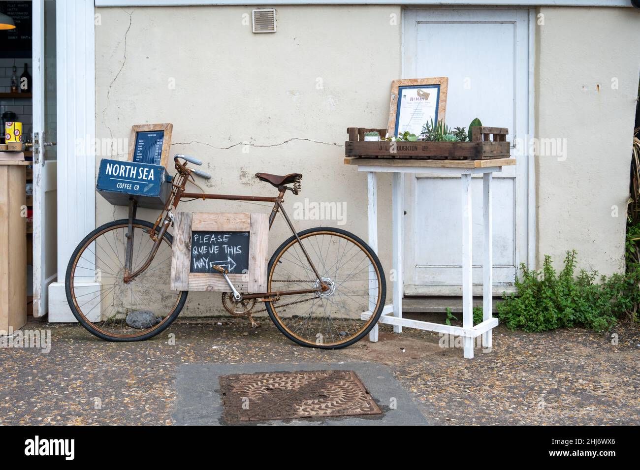 Ein altes Fahrrad vor der North Sea Coffee Company in Cromer diente als Werbetafel. Stockfoto