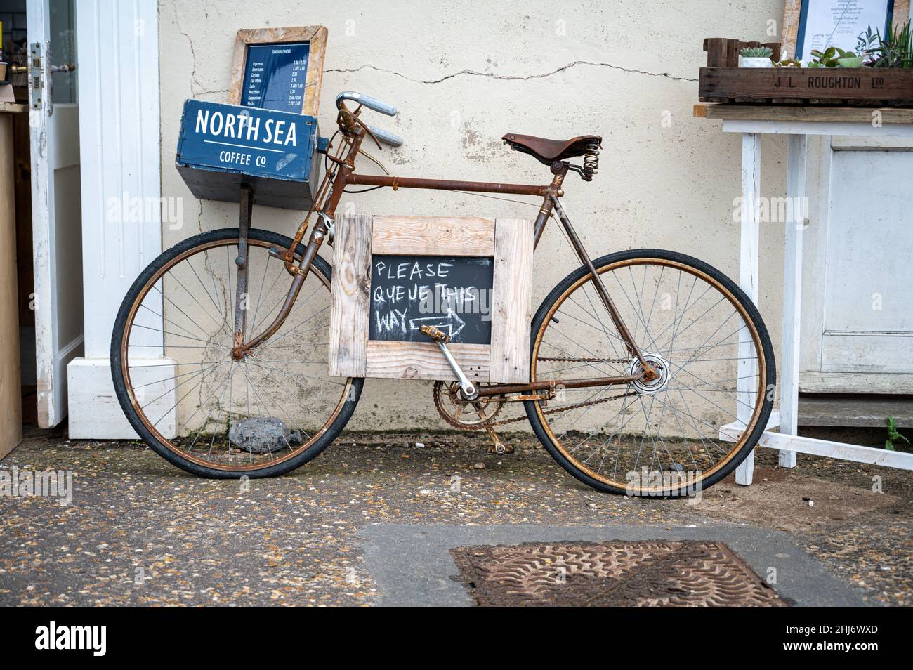 Ein altes Fahrrad vor der North Sea Coffee Company in Cromer diente als Werbetafel. Stockfoto