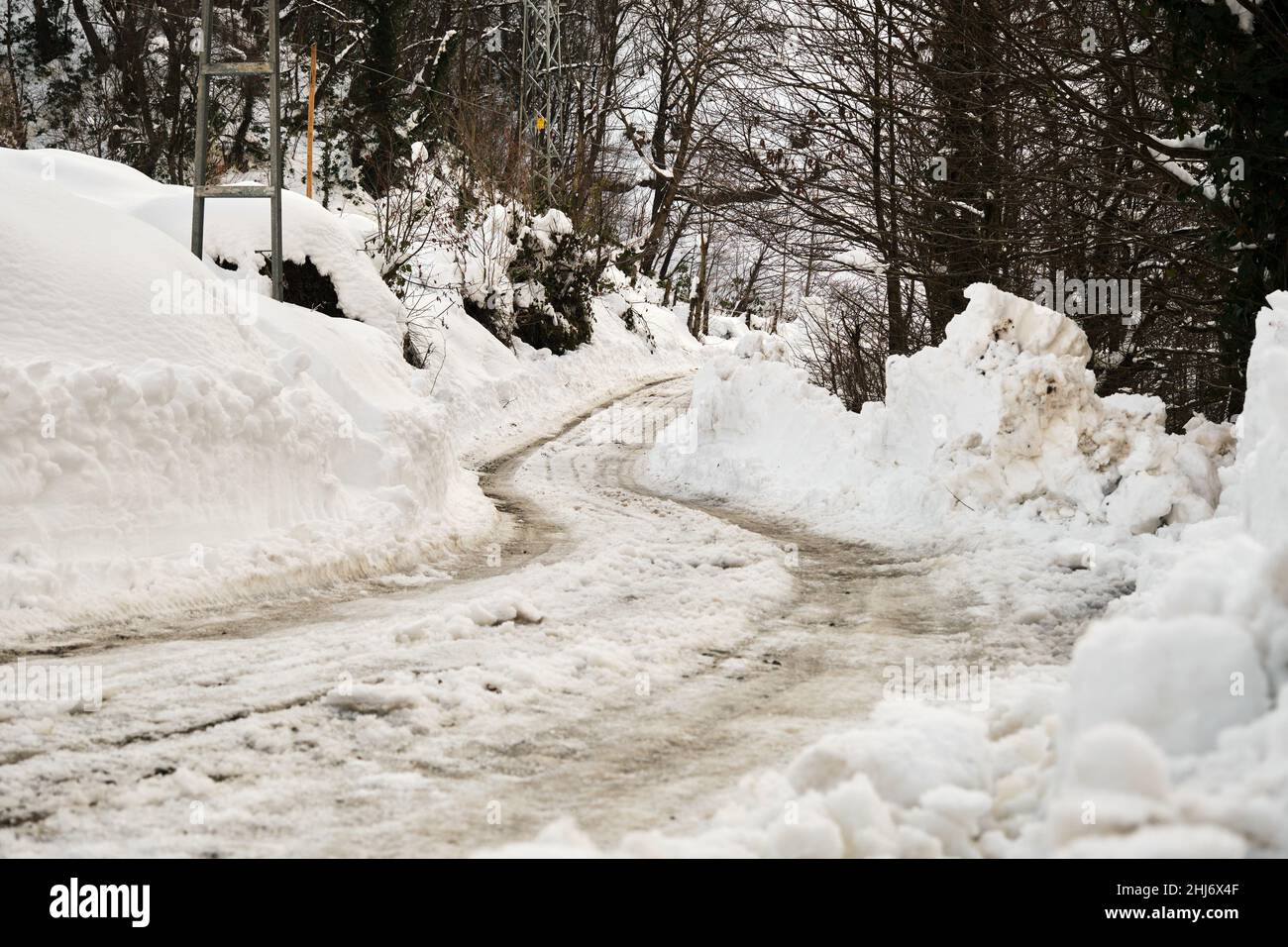 Straße von Schnee bedeckt, LKW Spuren auf der Straße. Eisgekühlter Weg in der Wintersaison Stockfoto