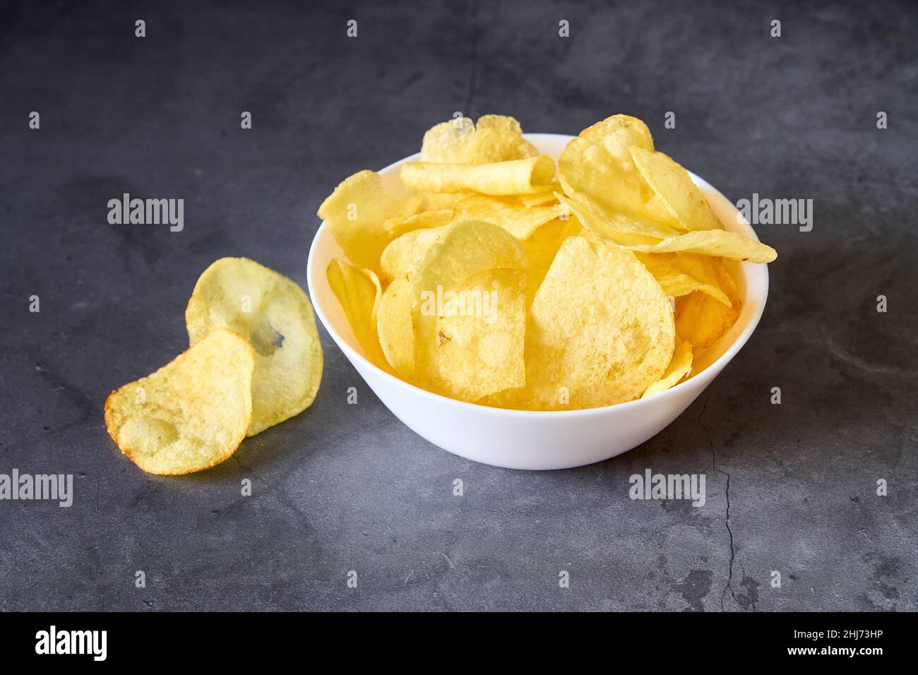 Eine weiße Schüssel mit pommes Frites auf schwarzem Schiefergrund Stockfoto