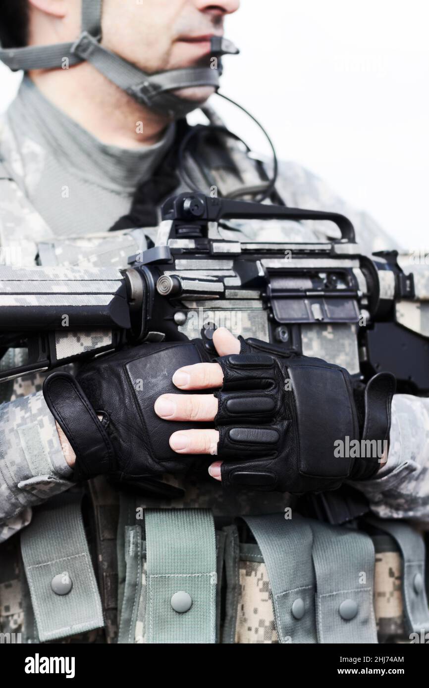 Soldat bereit zur Ruhe. Nahaufnahme eines Soldaten, der seine Waffe gegen seine Brust hält, in einem abgeschnittenen Schuss des Mittelriffs. Stockfoto