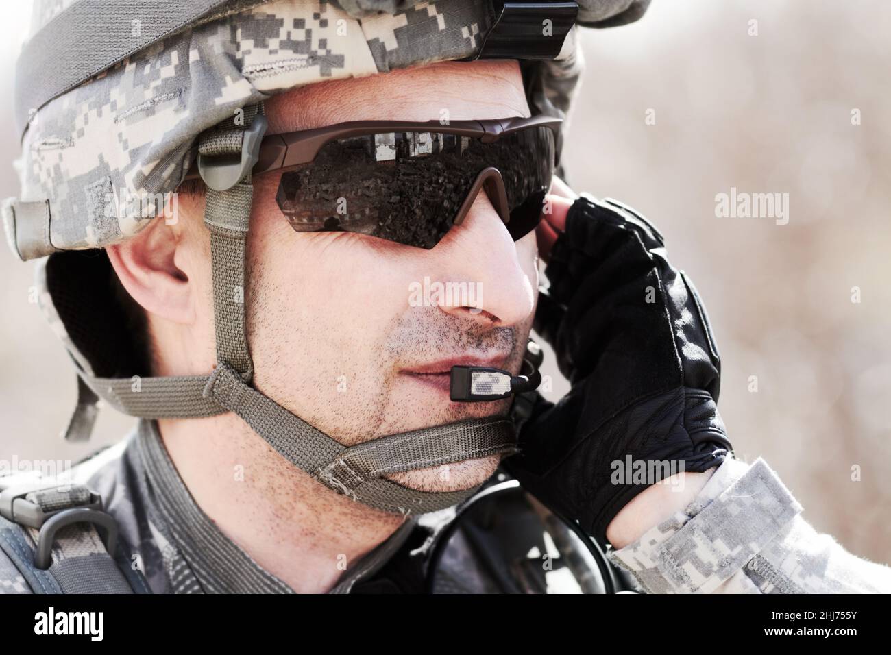Kommunikation auf dem Laufenden halten. Nahaufnahme eines Soldaten, der auf seinem Headset kommuniziert. Stockfoto