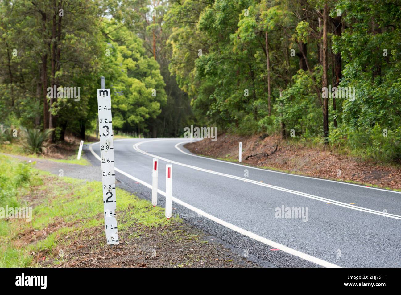 Ein Hochwassermeßschild auf einer tief liegenden Straße im regionalen Norden von New South Wales, Australien, das die Wassermenge über der Straße zeigt Stockfoto