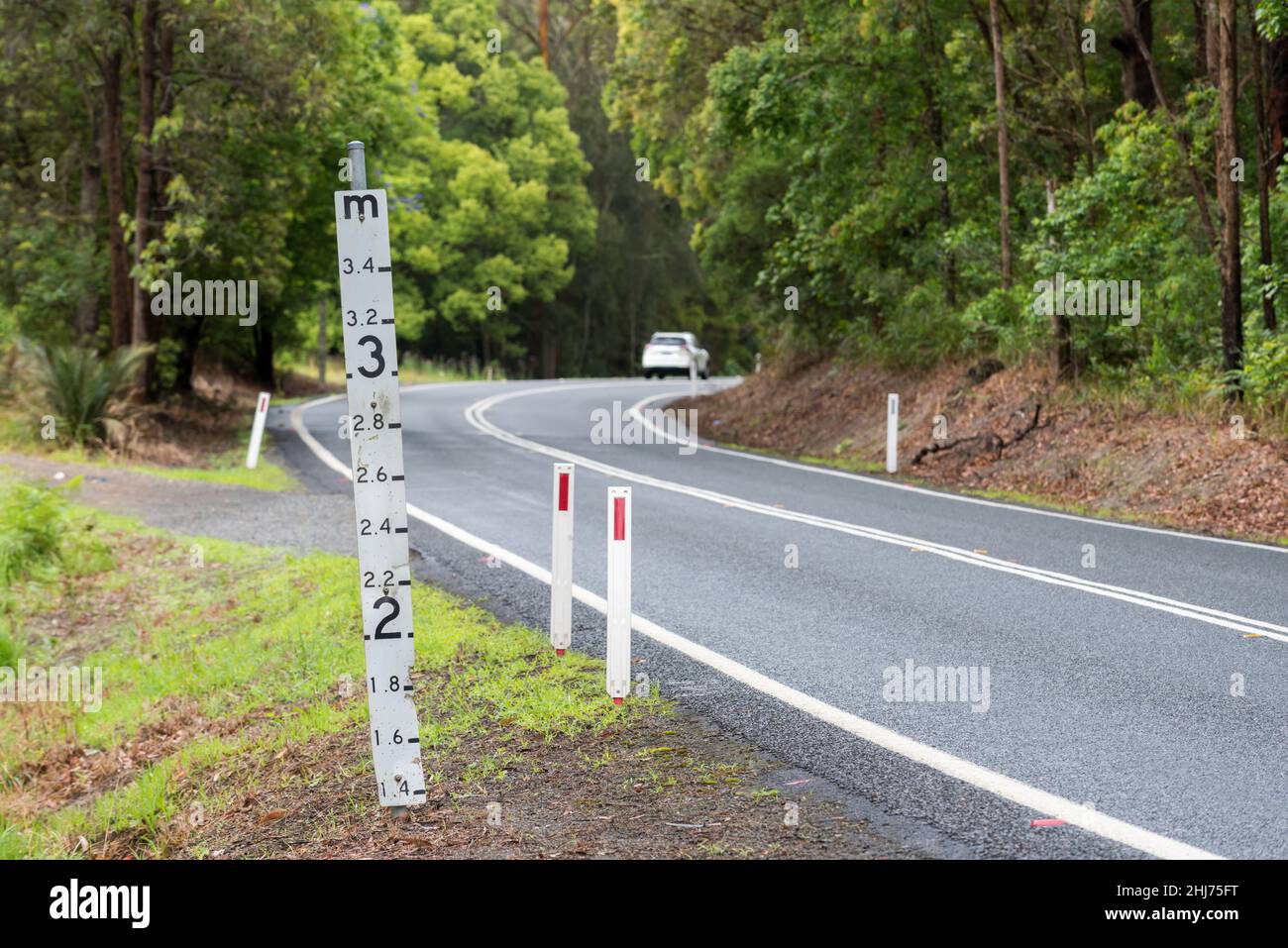 Ein Hochwassermeßschild auf einer tief liegenden Straße im regionalen Norden von New South Wales, Australien, das die Wassermenge über der Straße zeigt Stockfoto