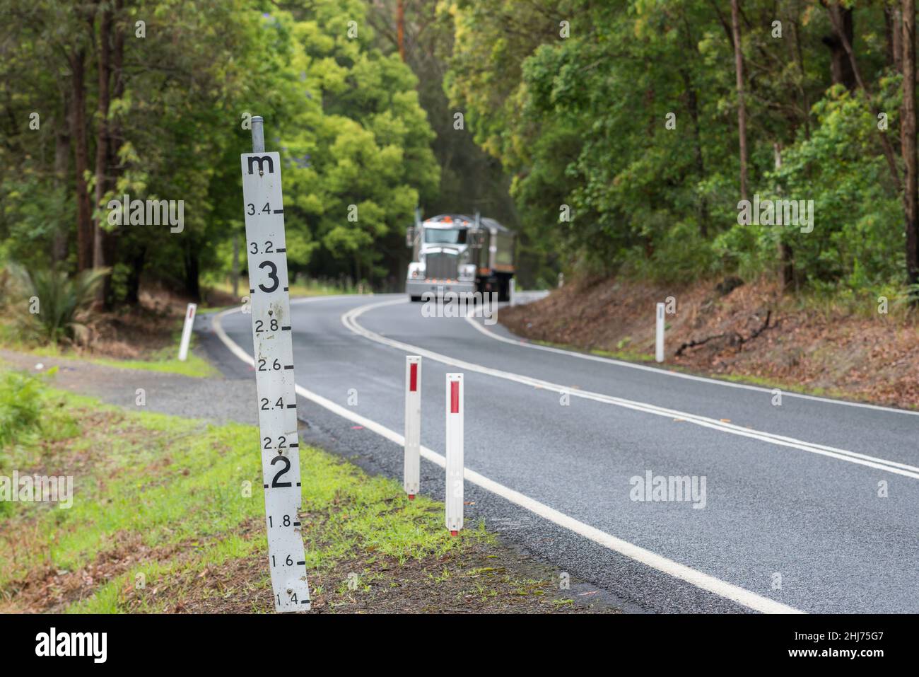 Ein Hochwassermeßschild auf einer tief liegenden Straße im regionalen Norden von New South Wales, Australien, das die Wassermenge über der Straße zeigt Stockfoto