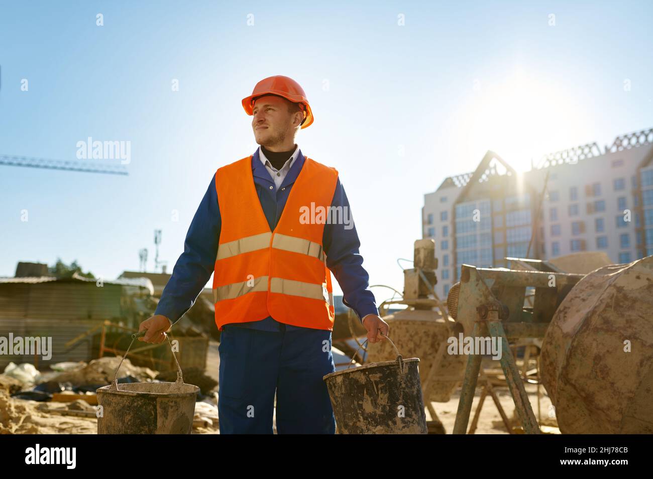 Baumeister hält Eimer über Baustelle Hintergrund Stockfoto