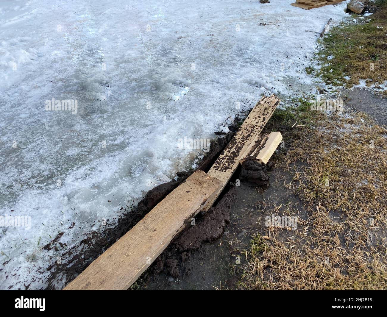 Holzbretter wurden verwendet, um das Auto aus dem Schlamm zu ziehen, um Traktion zu schaffen. Früher Frühling und nasse schlammige Wiese. Offroad. Stockfoto