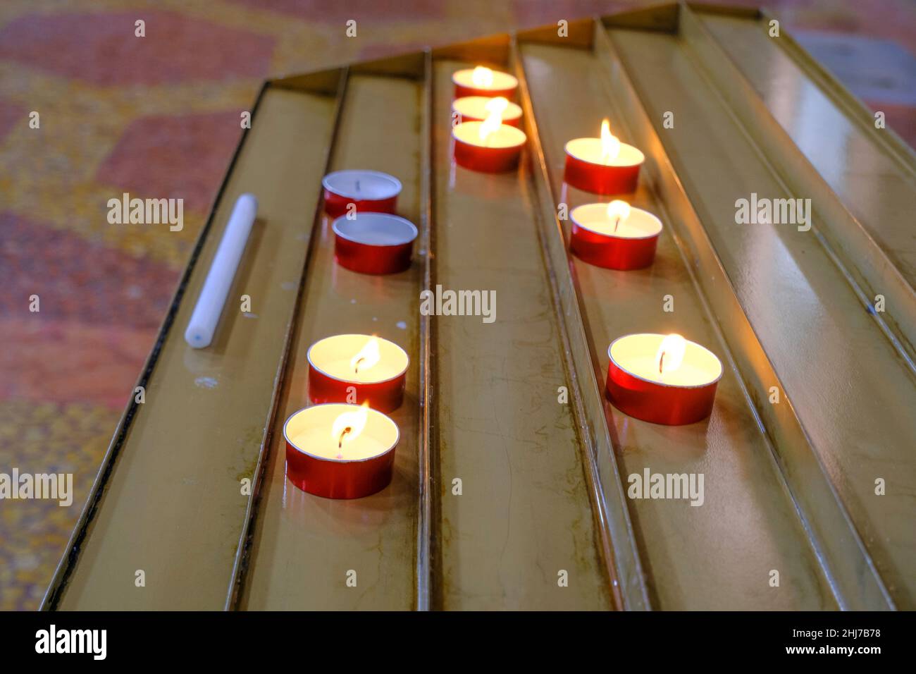 Tisch mit brennenden Kerzen aus der Nähe in der Kirche. Religionskonzept. Stockfoto