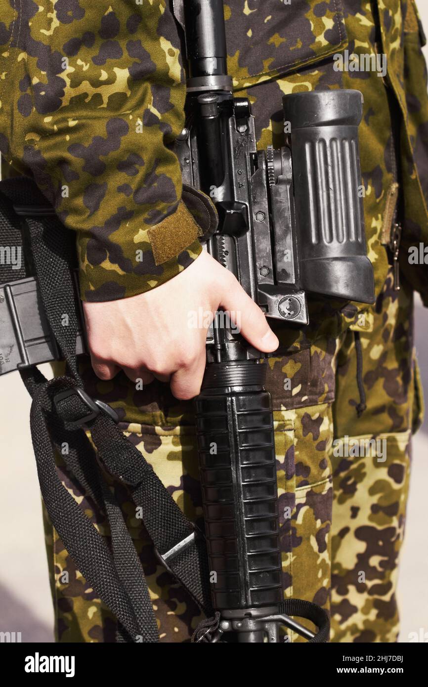 Seine zuverlässige Waffe. Zugeschnittenes Bild der Hand eines Soldaten, der ein Gewehr hält. Stockfoto