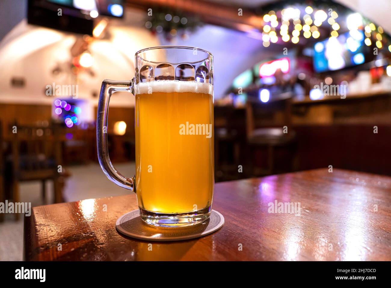 Ruhe. Volles Glas helles Lagerbier Holztisch in warmem Licht der Bar. Alkohol, Unterhaltung, traditionelle Getränke, Oktoberfest-Atmosphärenkonzept. Stockfoto