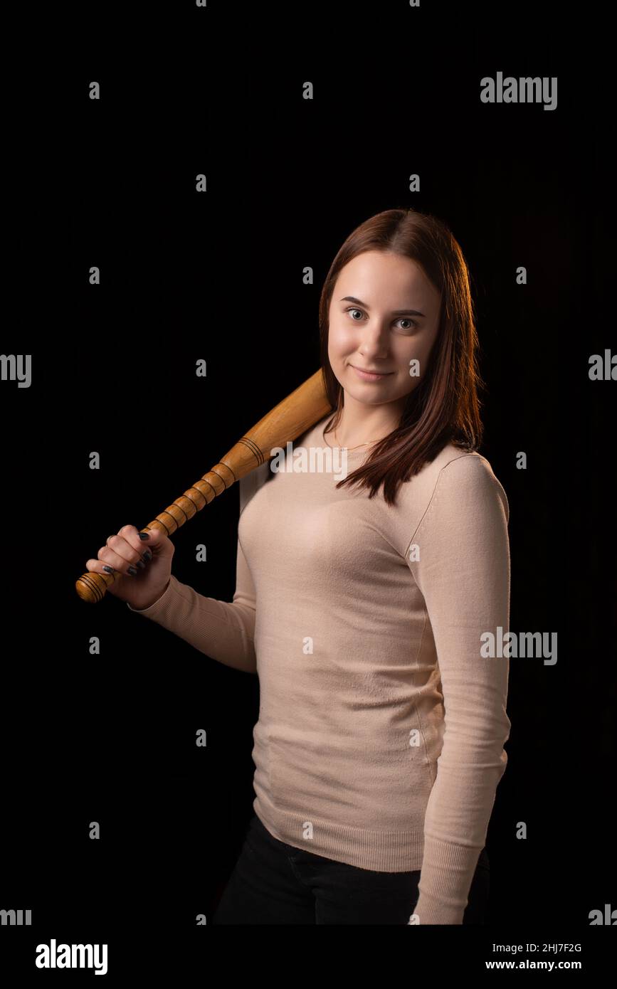 Junge Frau mit einer Fledermaus auf dunklem Hintergrund. Selbstverteidigung, psychologischer Schutz, mentale Stärke, inneres Friedenskonzept. Stockfoto