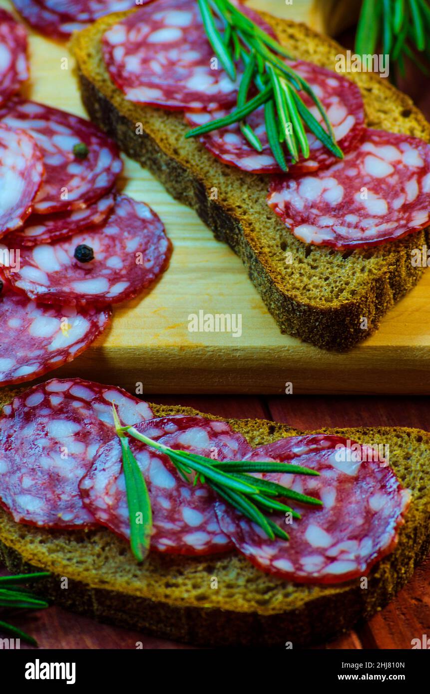 Würstchen-Sandwiches auf einem Holzbrett und Gewürze in der Nähe Stockfoto