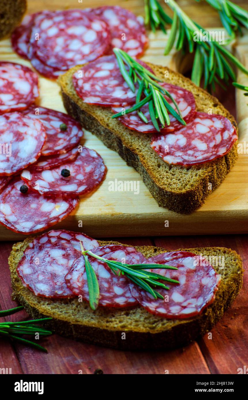 Würstchen-Sandwiches auf einem Holzbrett und Gewürze in der Nähe Stockfoto