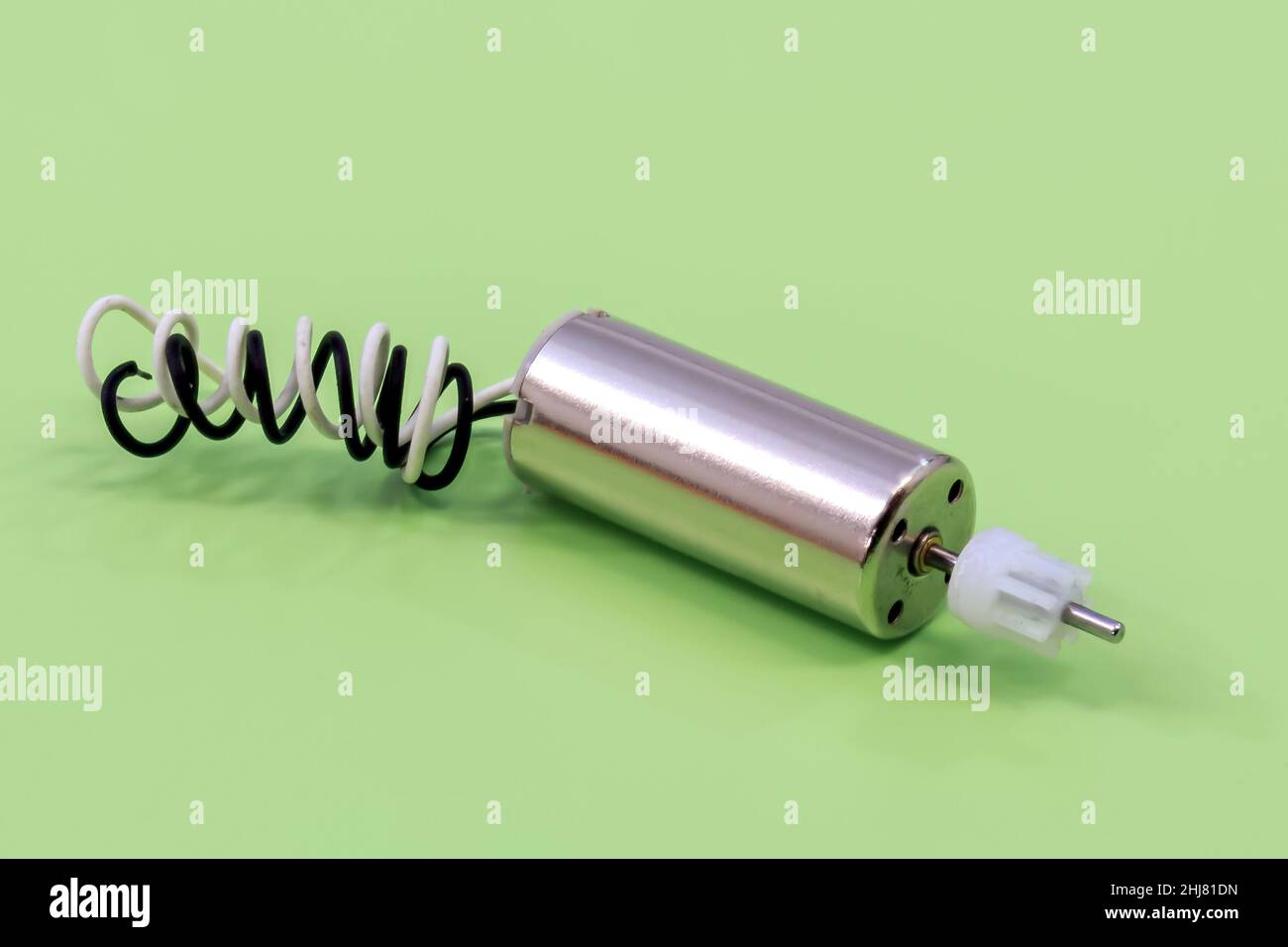 Nahaufnahme eines Miniatur-Elektromotors mit einem Nylongetriebe auf grünem Hintergrund Stockfoto