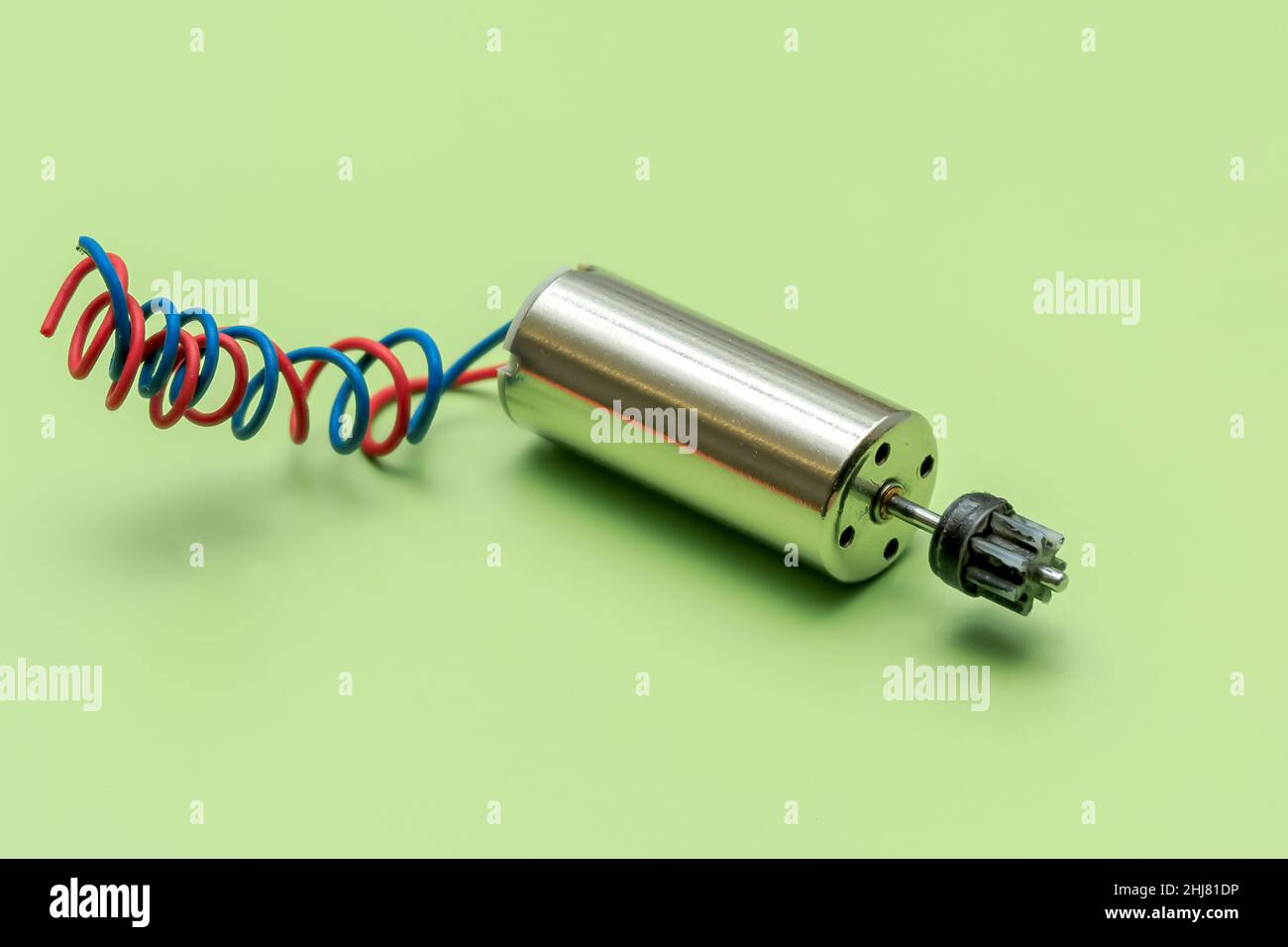 Nahaufnahme eines Miniatur-Elektromotors mit einem Nylongetriebe auf grünem Hintergrund Stockfoto