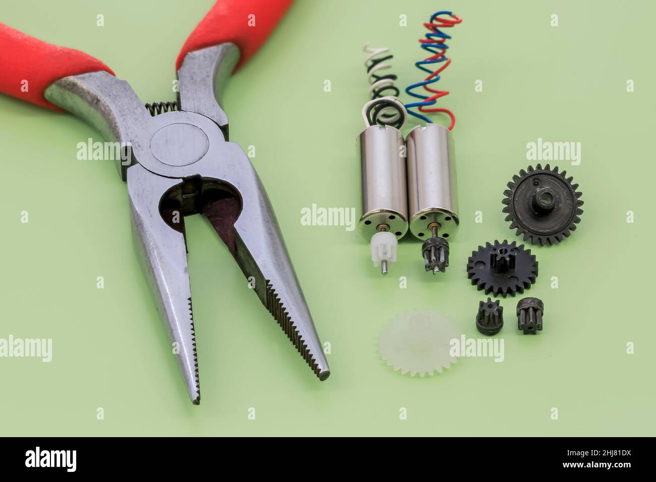 Nahaufnahme eines Miniatur-Elektromotors mit Nylongetrieben auf grünem Hintergrund Stockfoto