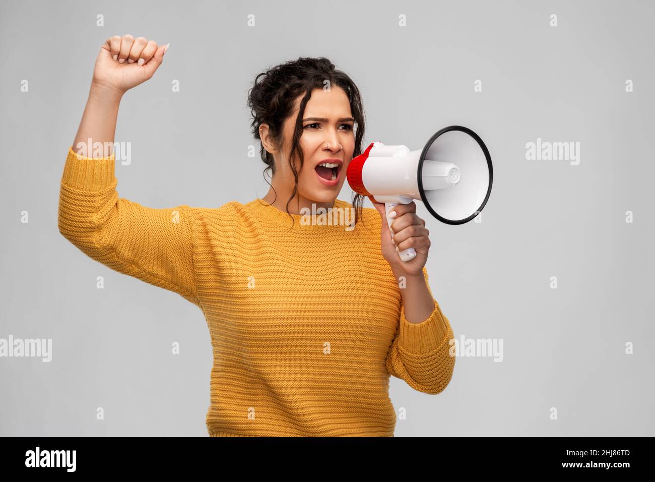 Wütende junge Frau, die mit dem Megaphon spricht Stockfoto
