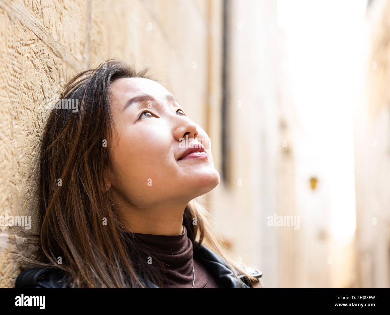 Porträt eines 29-jährigen asiatisch-amerikanischen Mädchens, das mit Gegenlicht aufschaut, Mdina, Malta Stockfoto