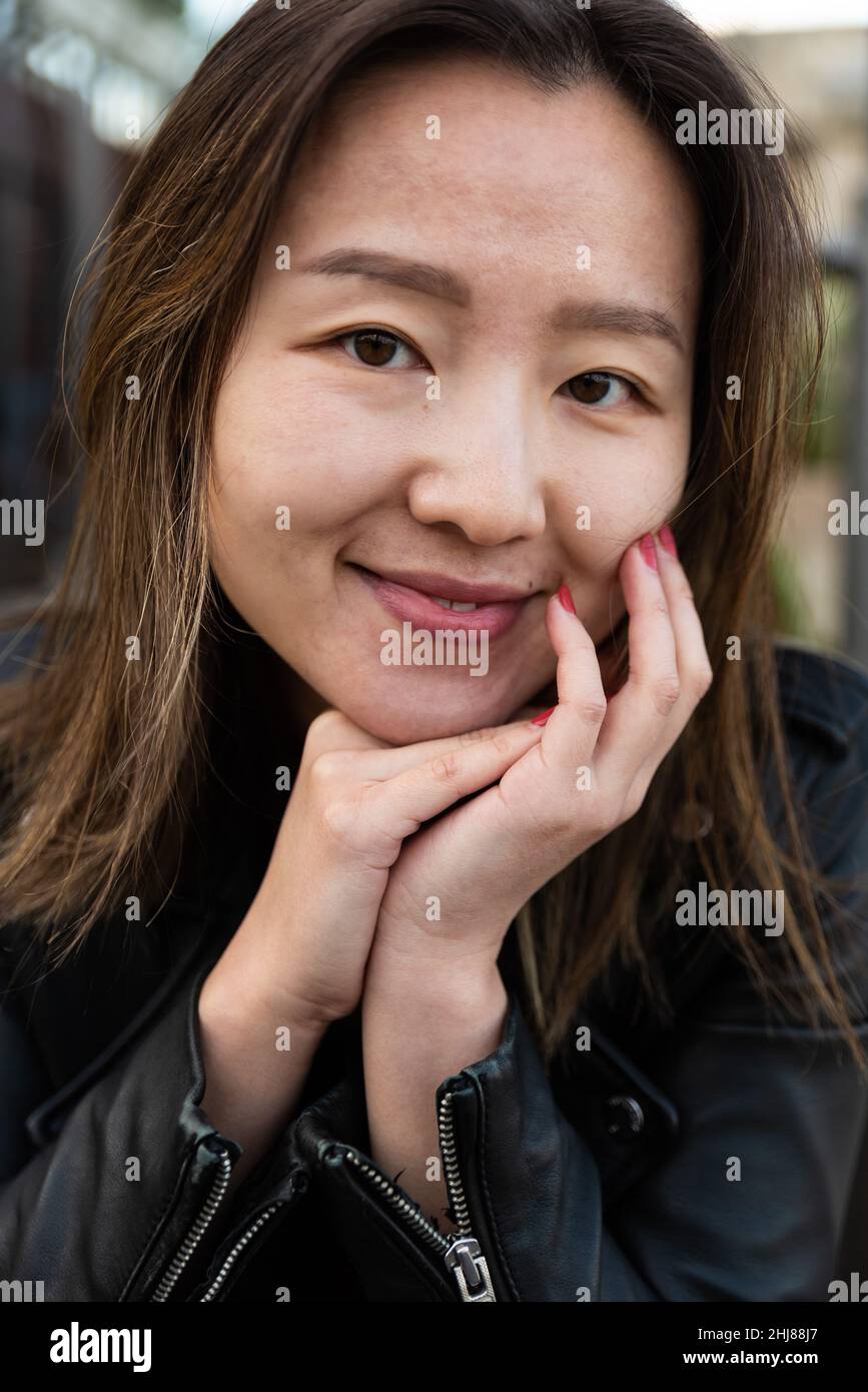 Nahaufnahme eines attraktiven asiatisch-amerikanischen Mädchens, das ihren Kopf auf den Händen hält Stockfoto