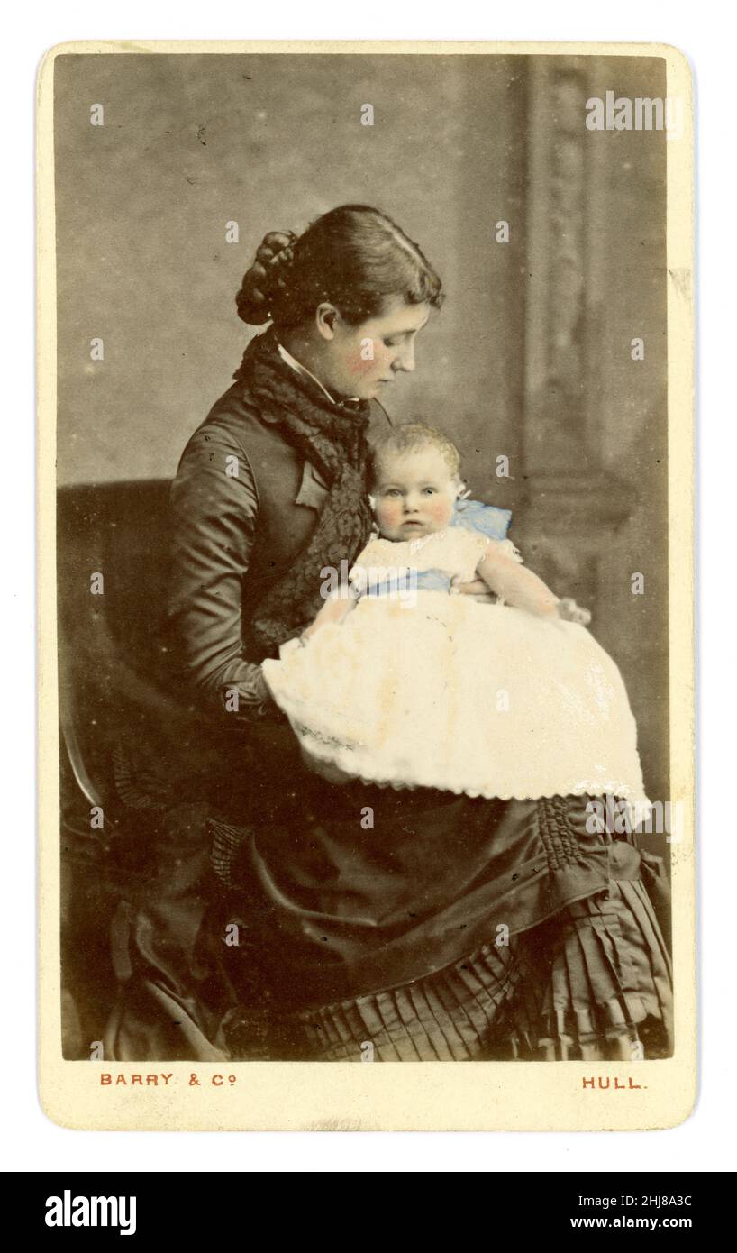 Original viktorianisch getönte Carte de Visite (CDV) von attraktiver Mutter, die ihr Baby zärtlich ansieht, das in einem weißen Kleid, möglicherweise einem Taufkleid, gekleidet ist. Die Frau hat eine Chignon-Frisur, und Kleid, das eine Hektik hat. Aus dem Studio von Barry & Co. Hull, Yorkshire, England, Großbritannien um 1875. Stockfoto